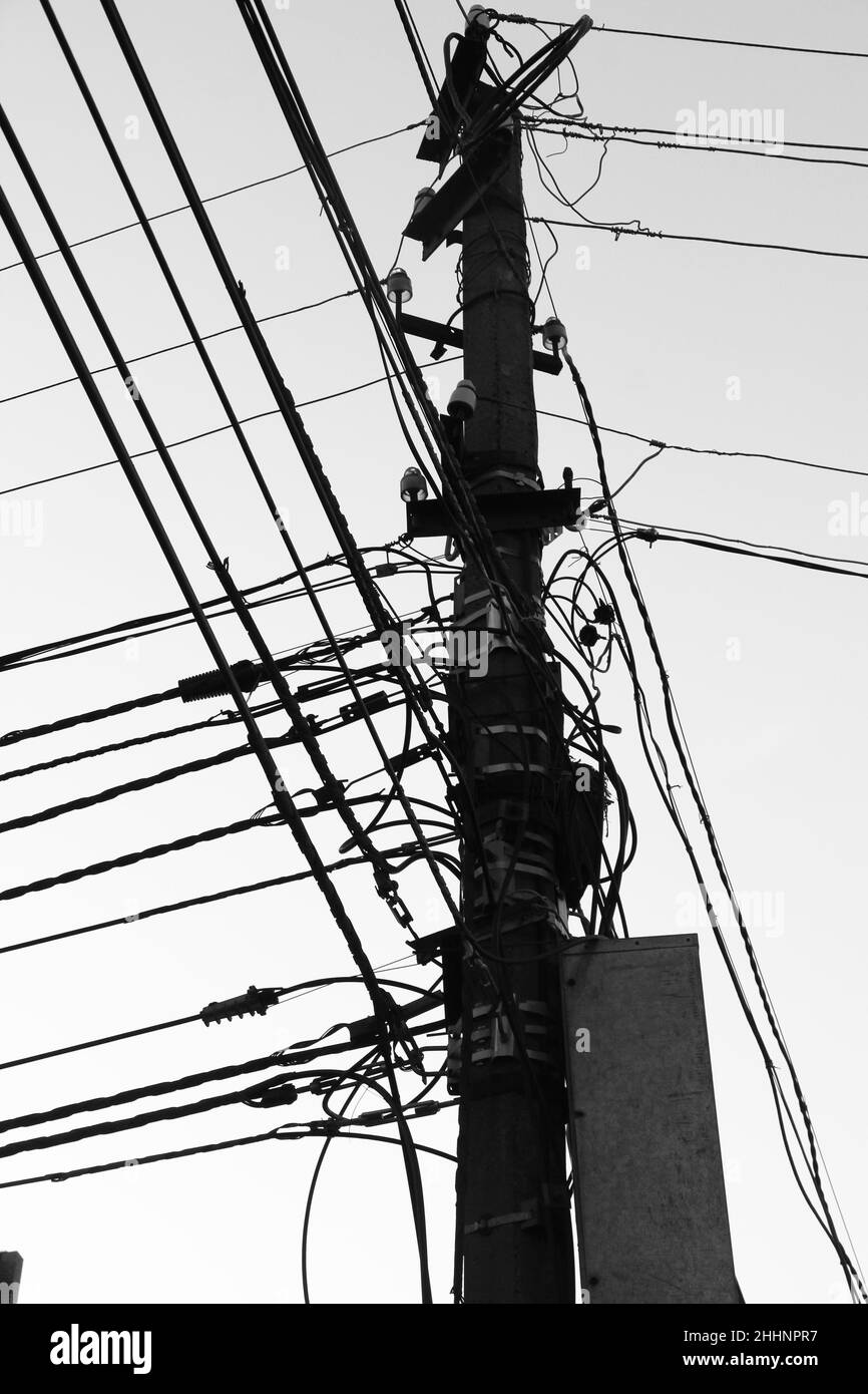 Colonna con fili elettrici contro il cielo. Scena urbana con comunicazioni tecniche. Linea di connessione Internet. Immagine in bianco e nero. Foto Stock