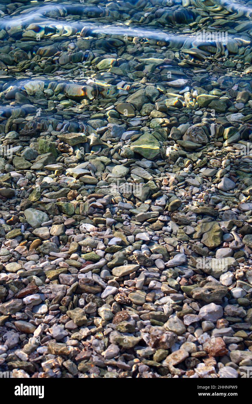 fondo pieno di ciottoli attraverso l'acqua limpida e trasparente del mare Foto Stock