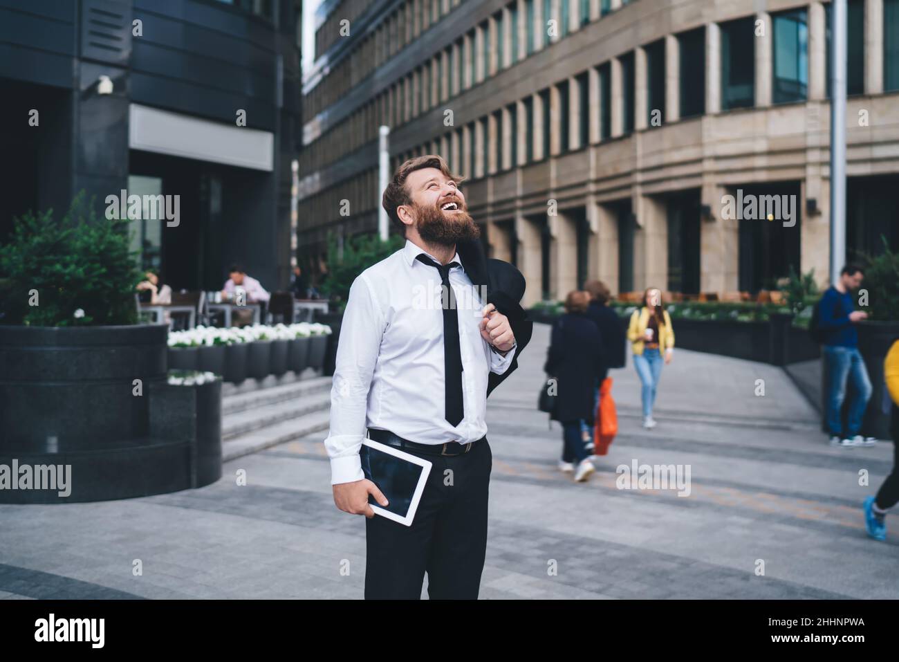 Uomo d'affari allegro con tablet in piedi sulla strada Foto Stock