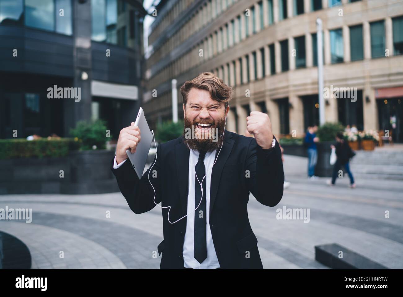 Uomo soddisfatto con tablet per strada Foto Stock