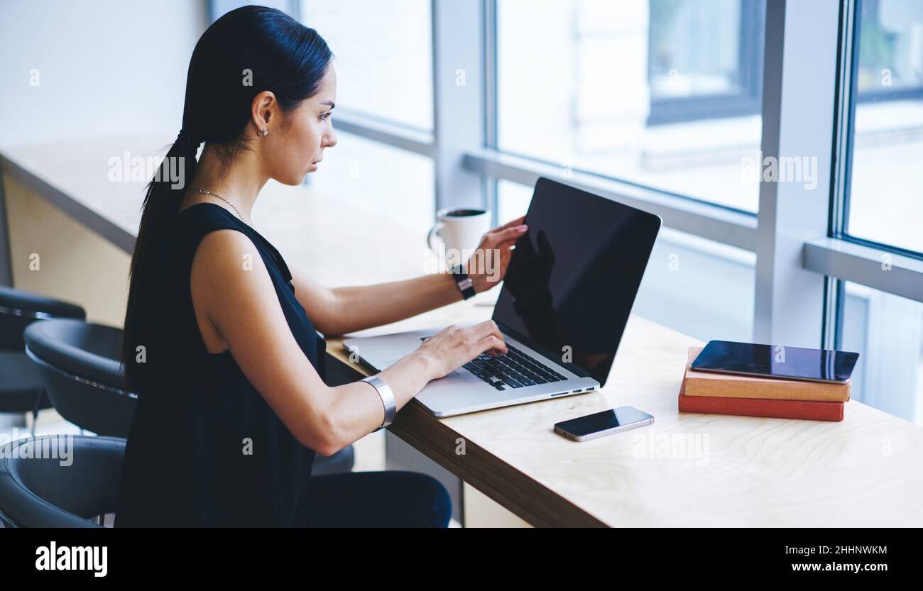 Freelance femminile focalizzata che naviga sul laptop nello spazio di lavoro Foto Stock