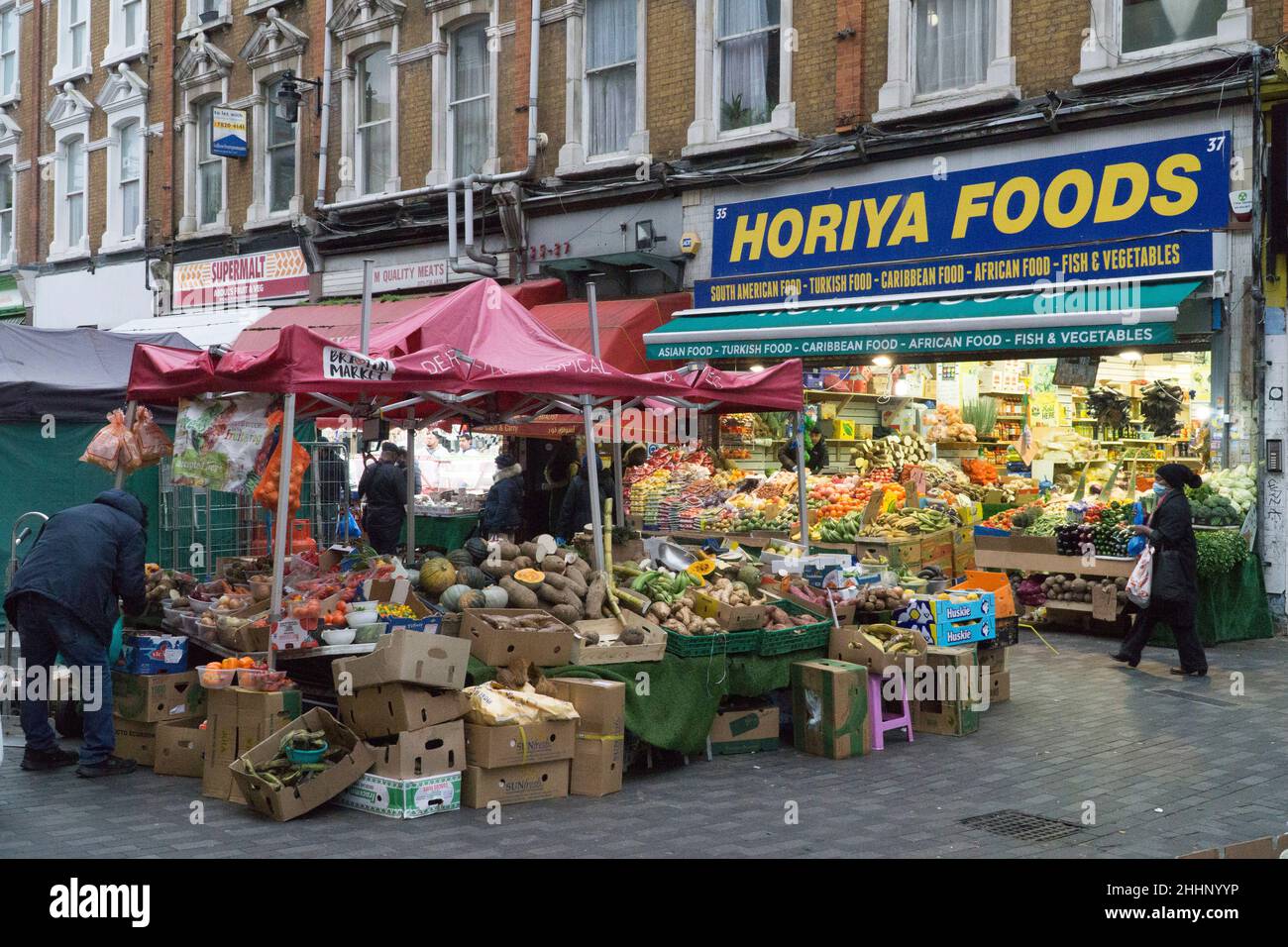 Londra, UK, 25 gennaio 2022: Su Electric Avenue a Brixton le persone acquistano generi alimentari da negozi e bancarelle del mercato che soddisfano la diversità della popolazione locale. Il costo degli alimenti di base è aumentato drasticamente e ci sono timori di come il costo della vita crisi influenzerà le famiglie più povere in tutto il paese. Anna Watson/Alamy Live News Foto Stock