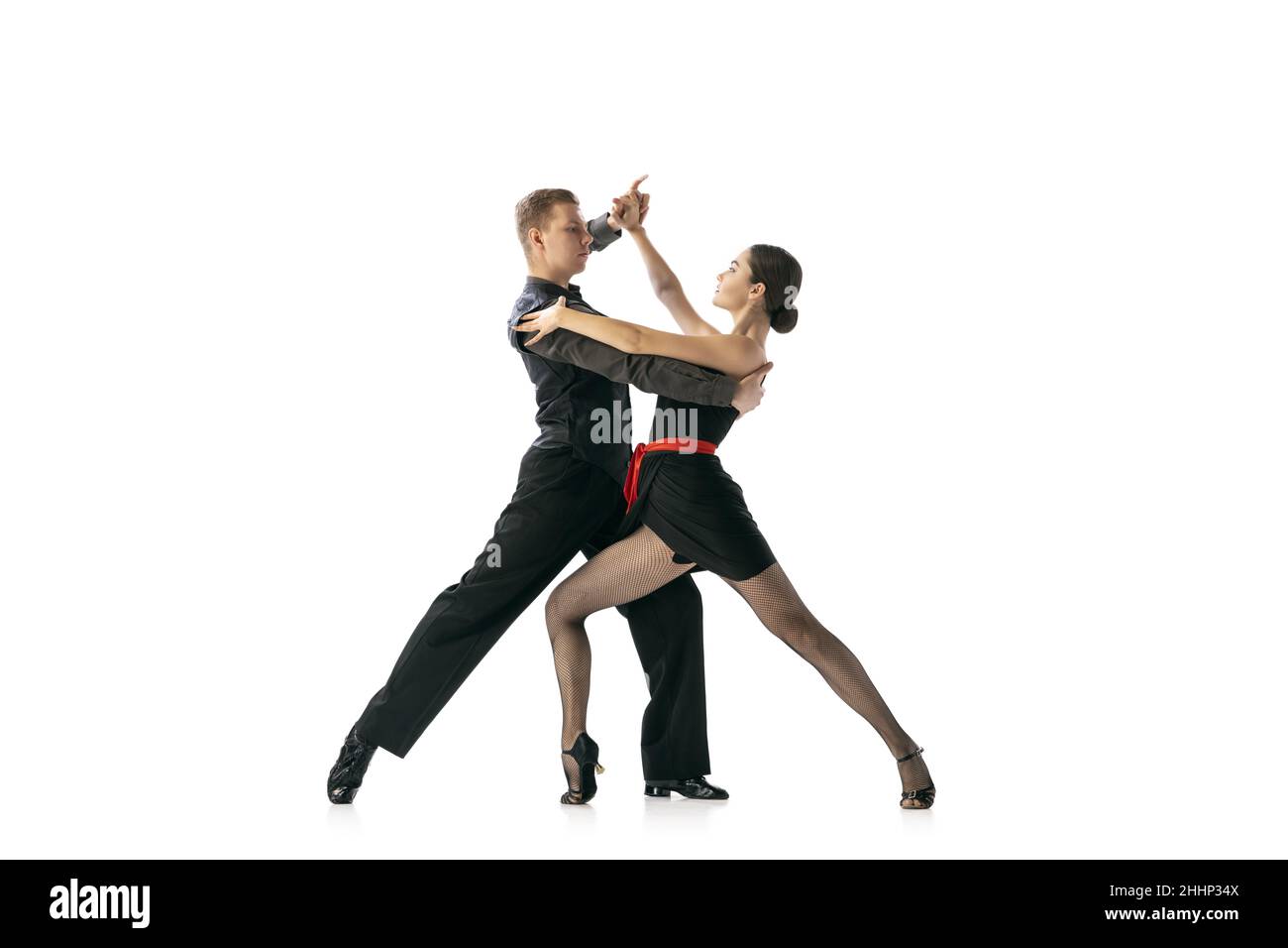 Flessibile giovane coppia danza tango argentino isolato su sfondo bianco studio. Artisti in costumi da palcoscenico nero Foto Stock