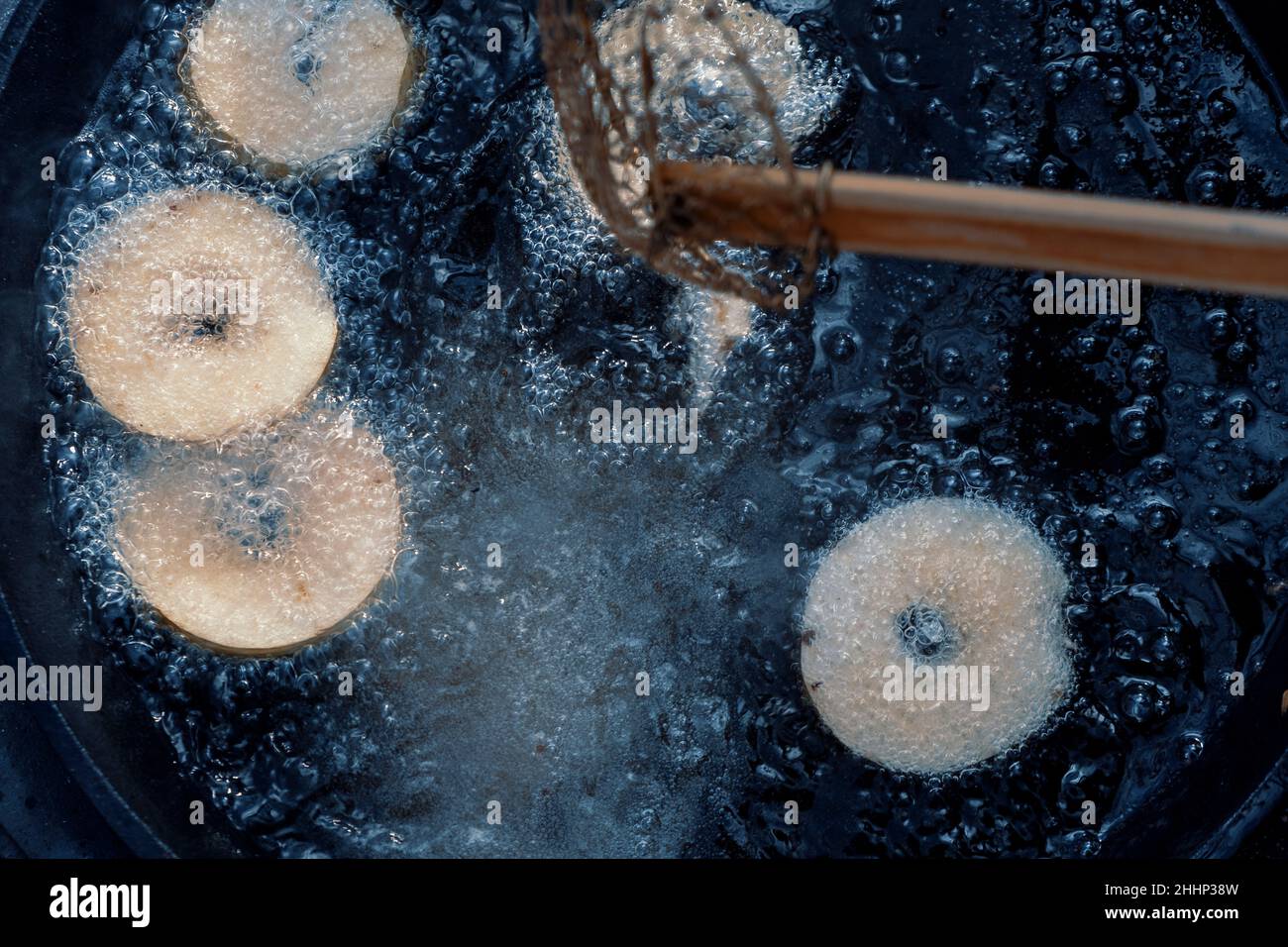 Ciambelle fatte in casa friggere in padella in ghisa all'aperto al campeggio. Foto Stock