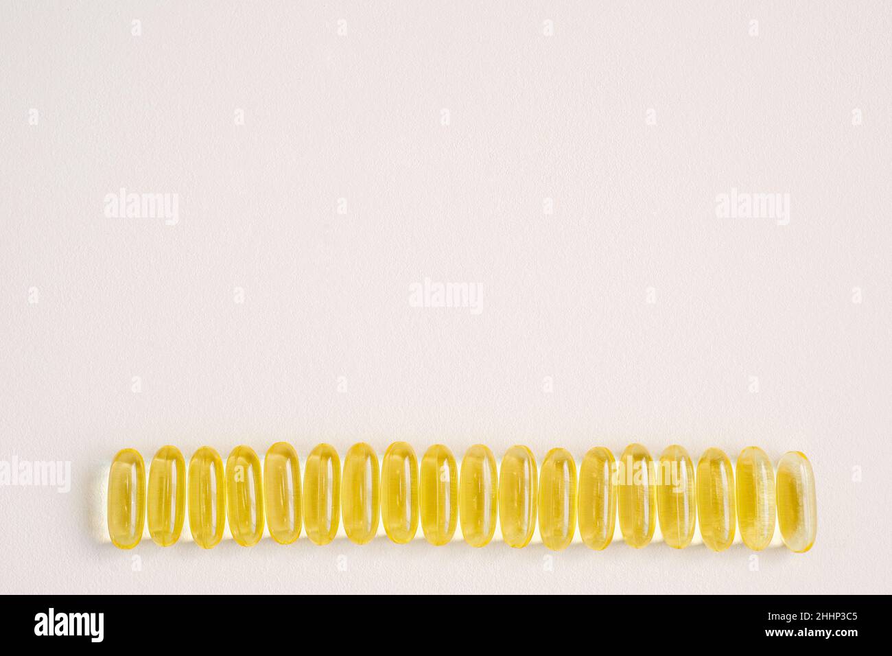 Le capsule di gel molle si trovano in una fila. Integrazione con vitamina D3, gruppo di pillole su uno sfondo rosa neutro con spazio di copia per il testo. Foto Stock