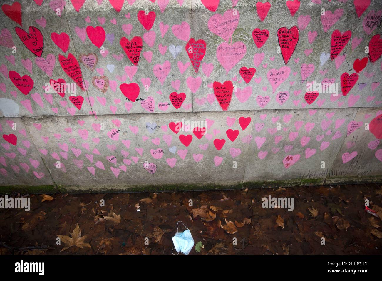 Una maschera è vista a sinistra sotto i cuori rossi, che rappresentano coloro che sono morti di Covid-19, sul National Covid Memorial Wall lungo il Tamigi a Londra. Foto Stock