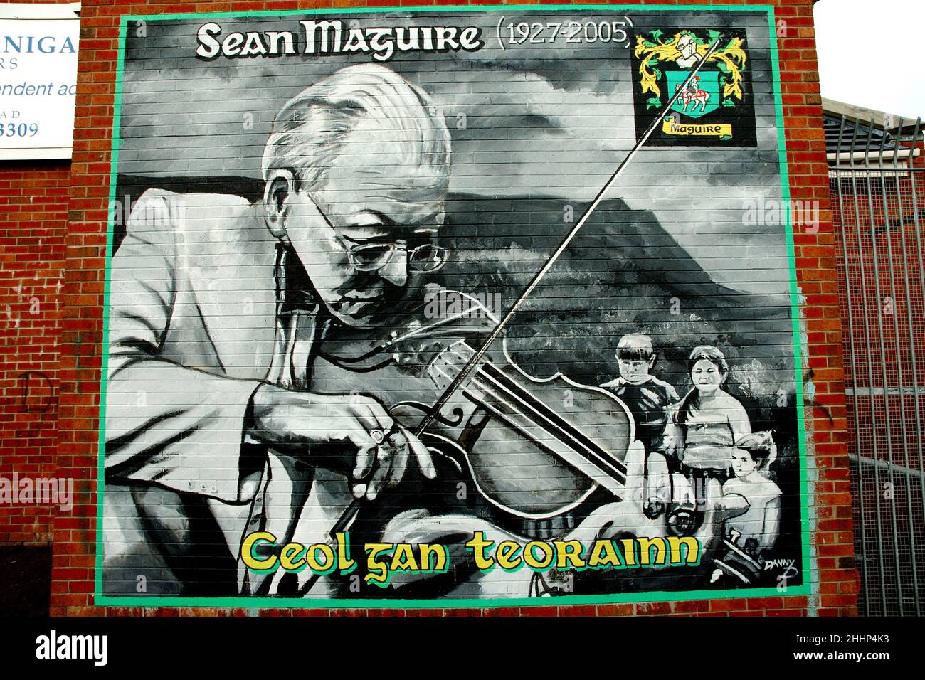 Irlanda del Nord. Ulster. Belfast. Cade su strada. Murale nel distretto cattolico in memoria del fiddler Sean Maguire, campione della cultura gaelica. Foto Stock