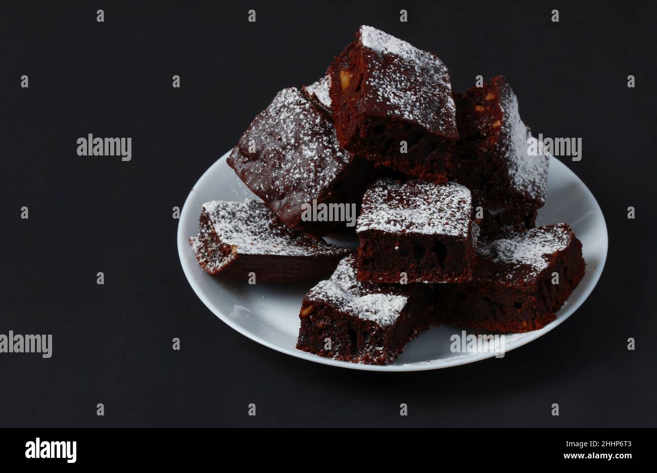 Pezzetti di torta al caffè cosparsi di zucchero a velo su un piatto di porcellana bianca Foto Stock