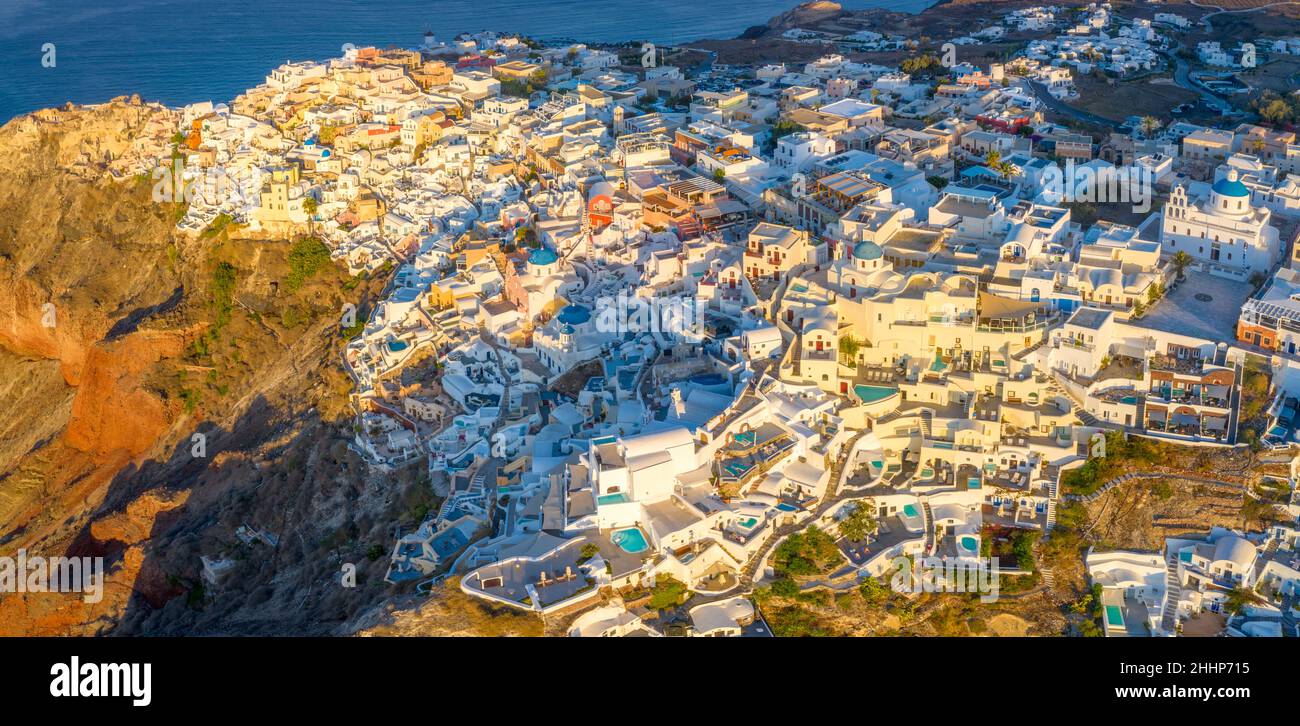 Pittoresca vista aerea drone del famoso villaggio di Oia con case bianche durante l'alba sull'isola di Santorini, Grecia, Europa. Viaggi di lusso. Vacanze estive Foto Stock