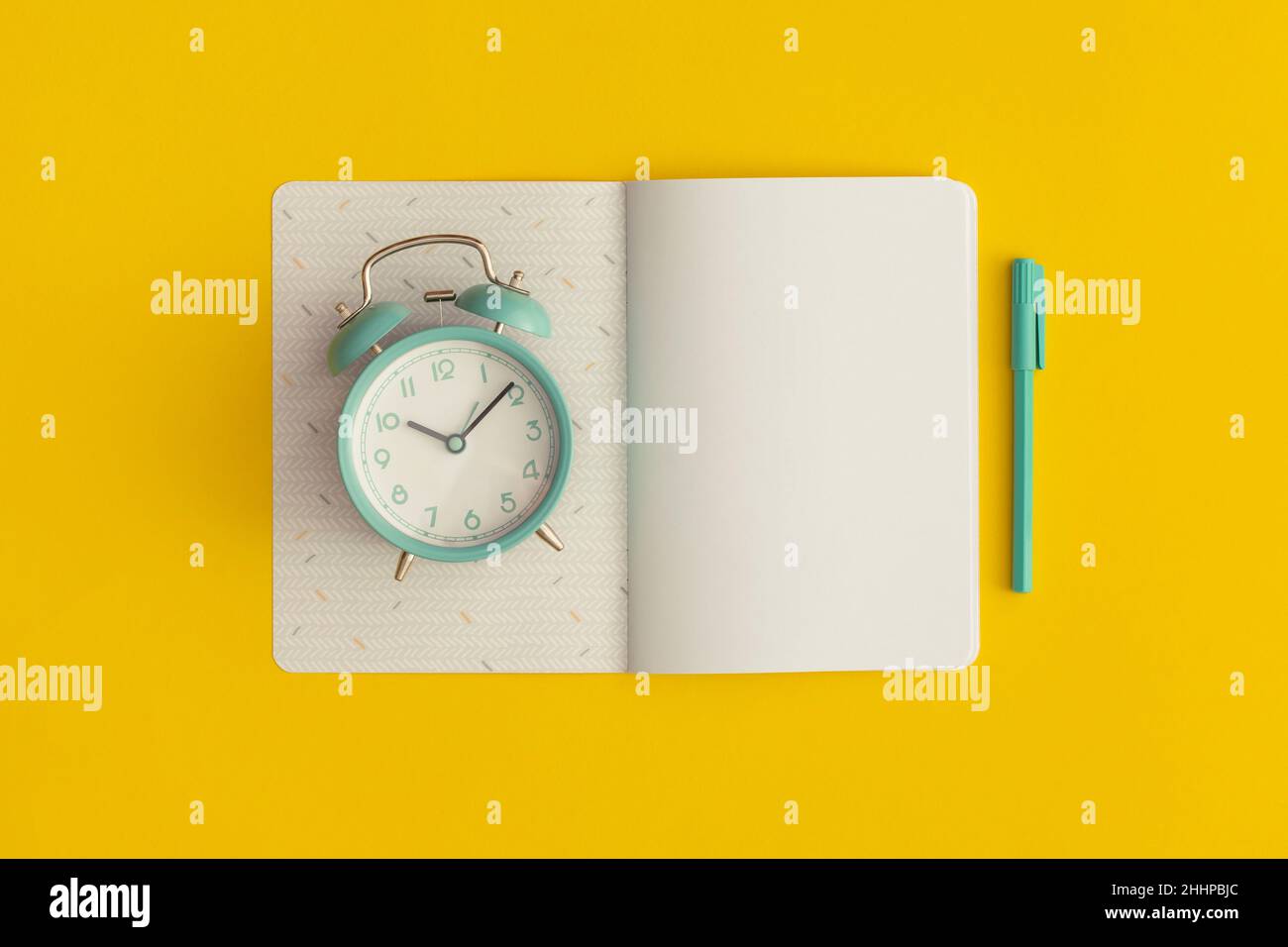 Notebook, sveglia e penna su sfondo giallo. Vista dall'alto. Disposizione piatta. Concetto di ritorno a scuola. Foto Stock