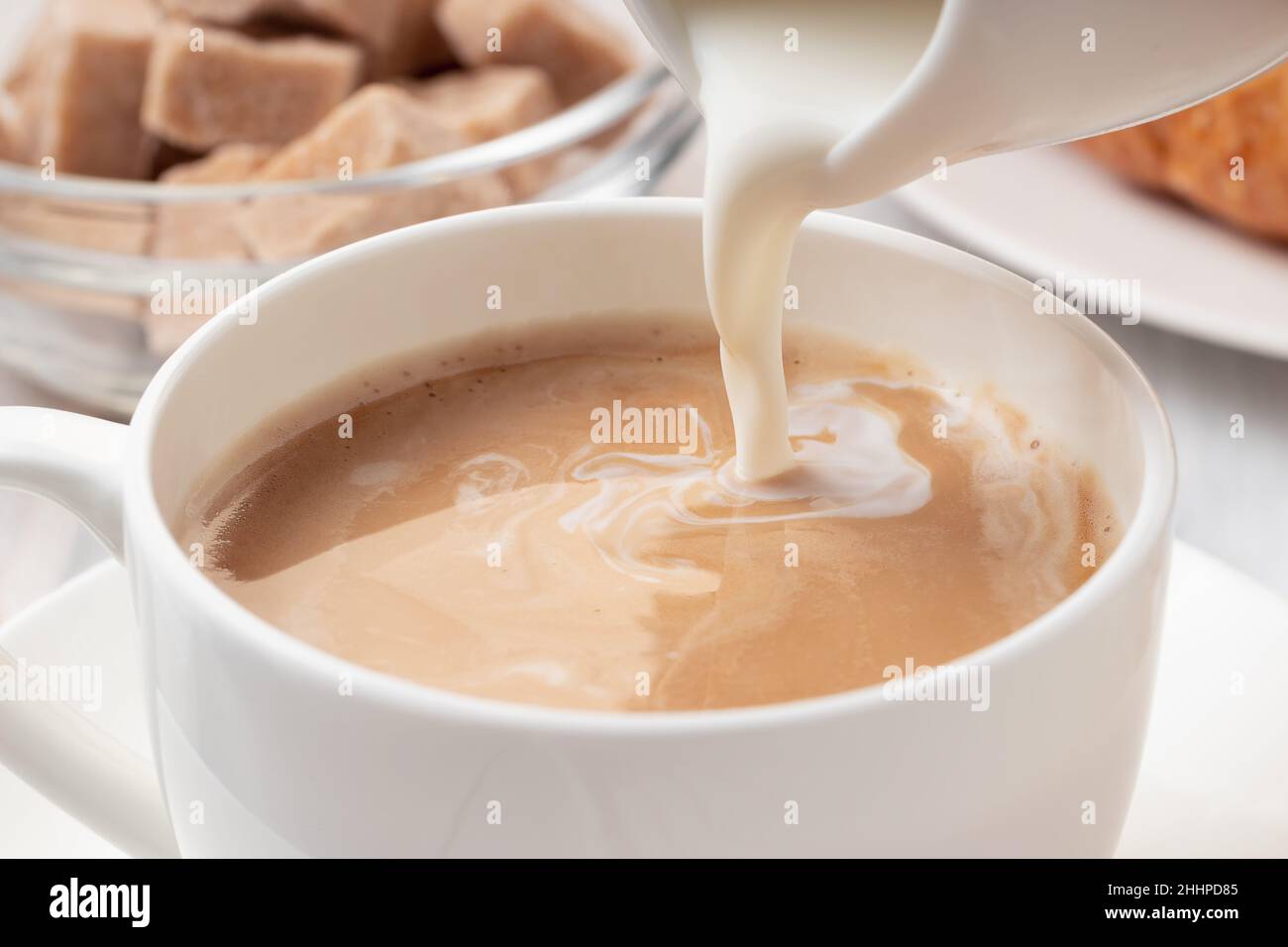 Versare il latte o la panna in un caffè appena fatto, primo piano Foto Stock