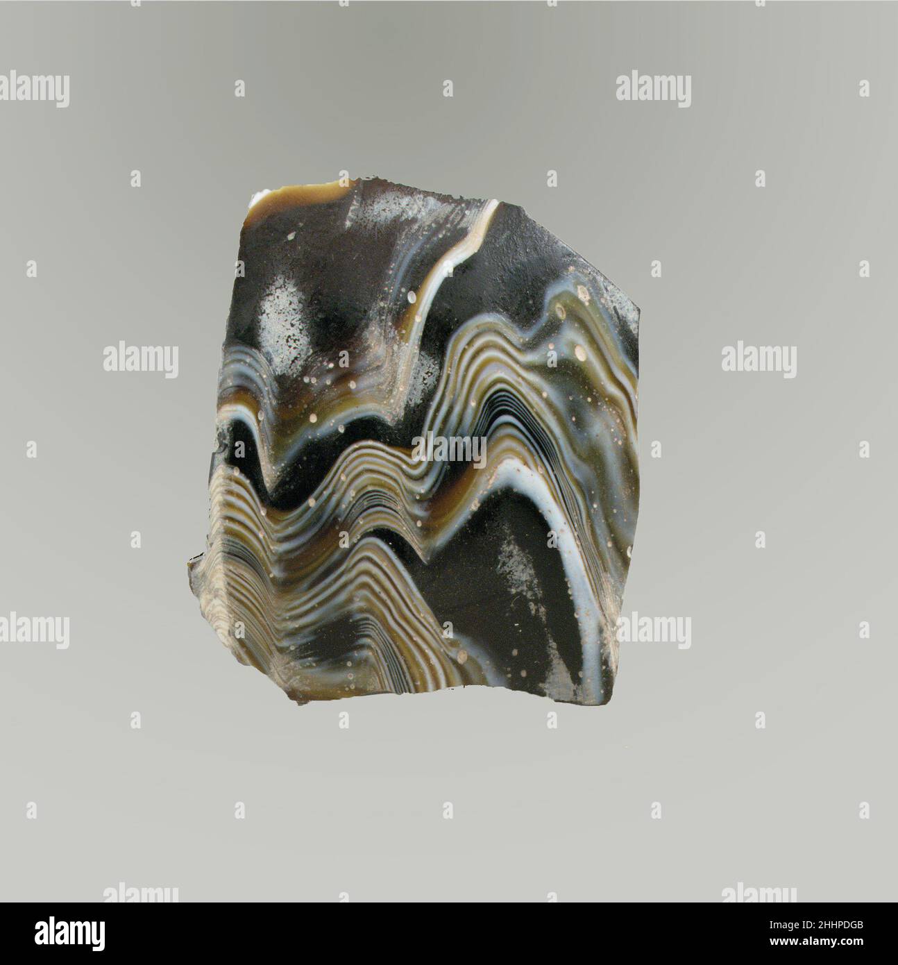 Mosaico di vetro dentellata ciotola frammento fine 1st secolo a.C.–inizio 1st secolo d.C. frammento di corpo romano, sottile-murato.traslucido profondo miele marrone e bianco opaco.lato curvo di Convex rastremato verso il basso.motivo di mosaico di nastro formato da sezioni di un singolo bastone in marrone macinato con fili bianchi ondulati irregolari in linee parallele; Sull'esterno, tre nervature poco profonde verticali, abbastanza ampiamente distanziate, con i bordi esterni arrotondati e terminanti intorno a bottom.Polished esterno; vaiolatura delle bolle di superficie e piccole zone di tempo cremoso sul esterno; iiridescent cremoso che copre l'interno; alcuno Foto Stock