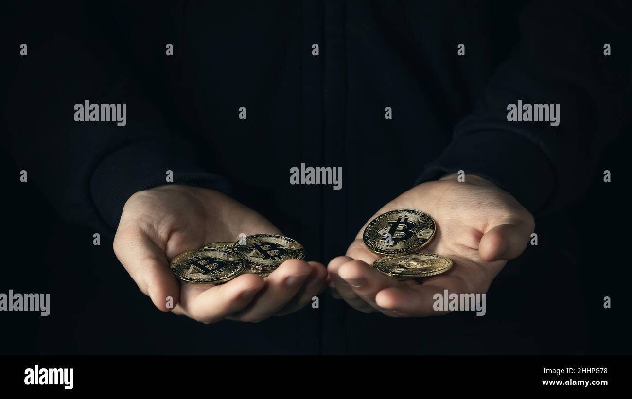 Manciata di bitcoins in palmson maschio uno sfondo scuro. Risparmio finanziario, accumulo nel concetto di criptovaluta. Messa a fuoco selettiva. Foto Stock
