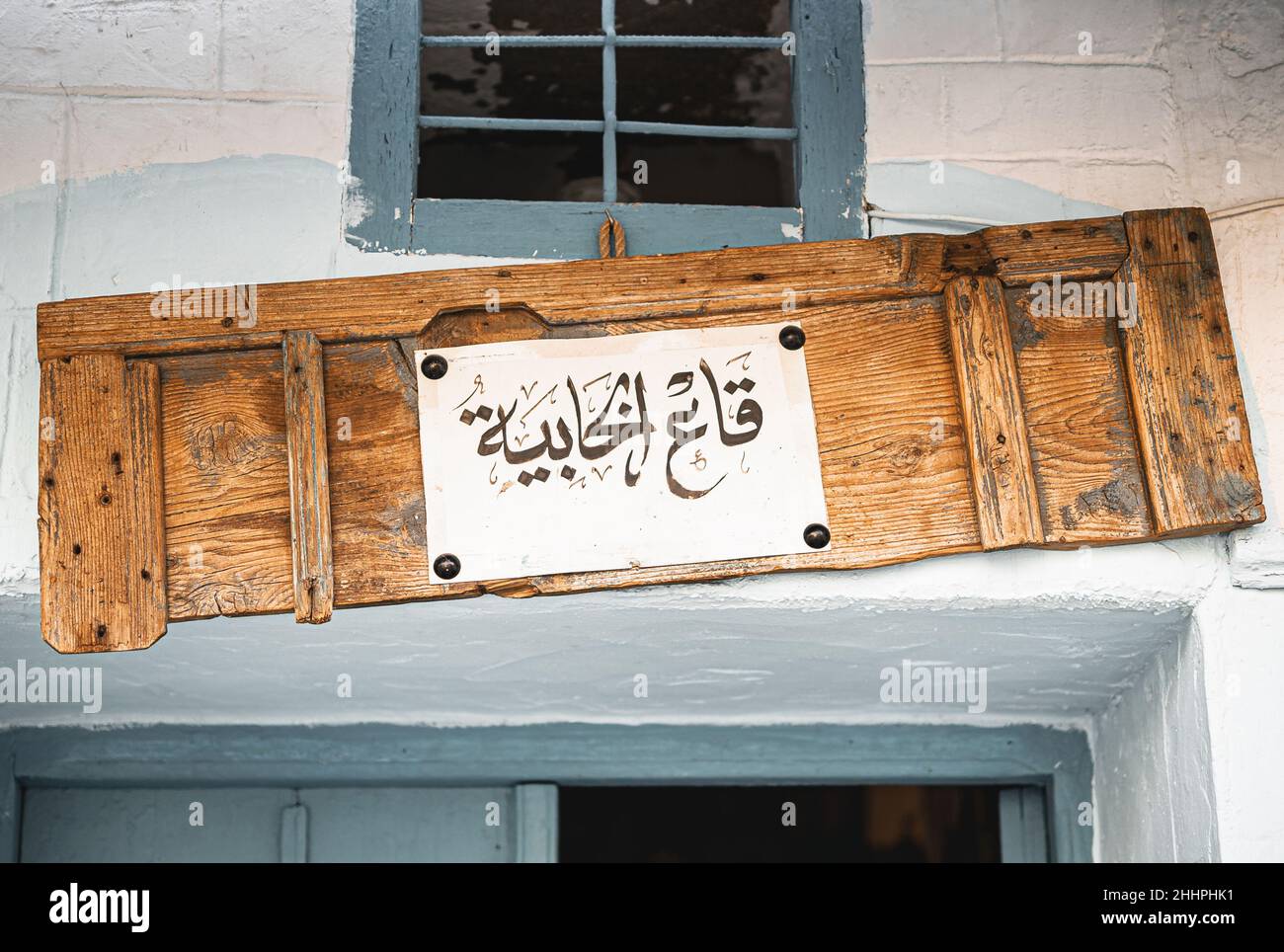 Un nome di un negozio tradizionale a Tunisi scritto su una vecchia porta di legno in una calligrafia arabica Foto Stock