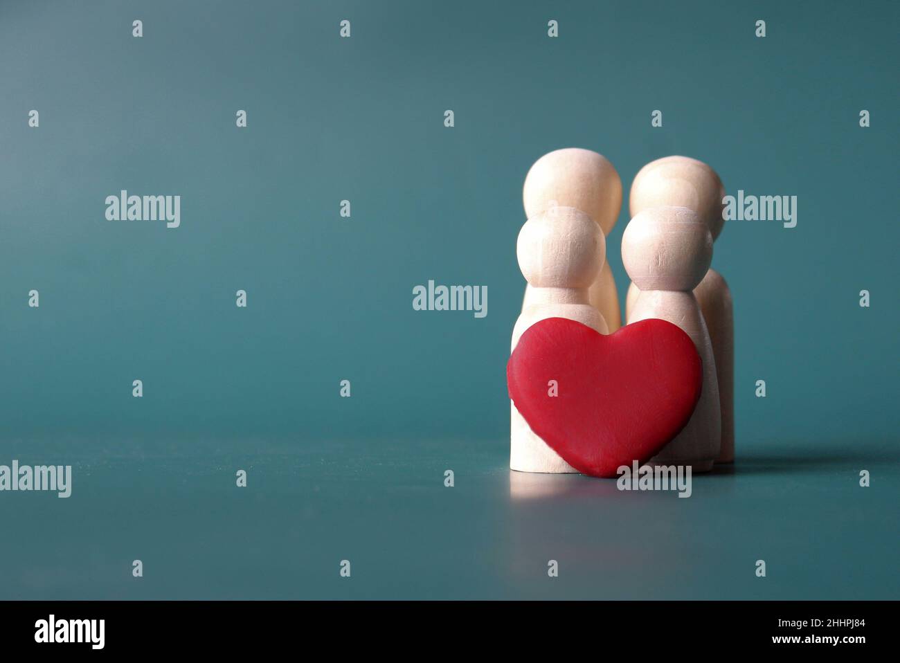 Famiglia, rapporto e concetto di amore. Bambole in legno e cuore rosso con spazio copia Foto Stock