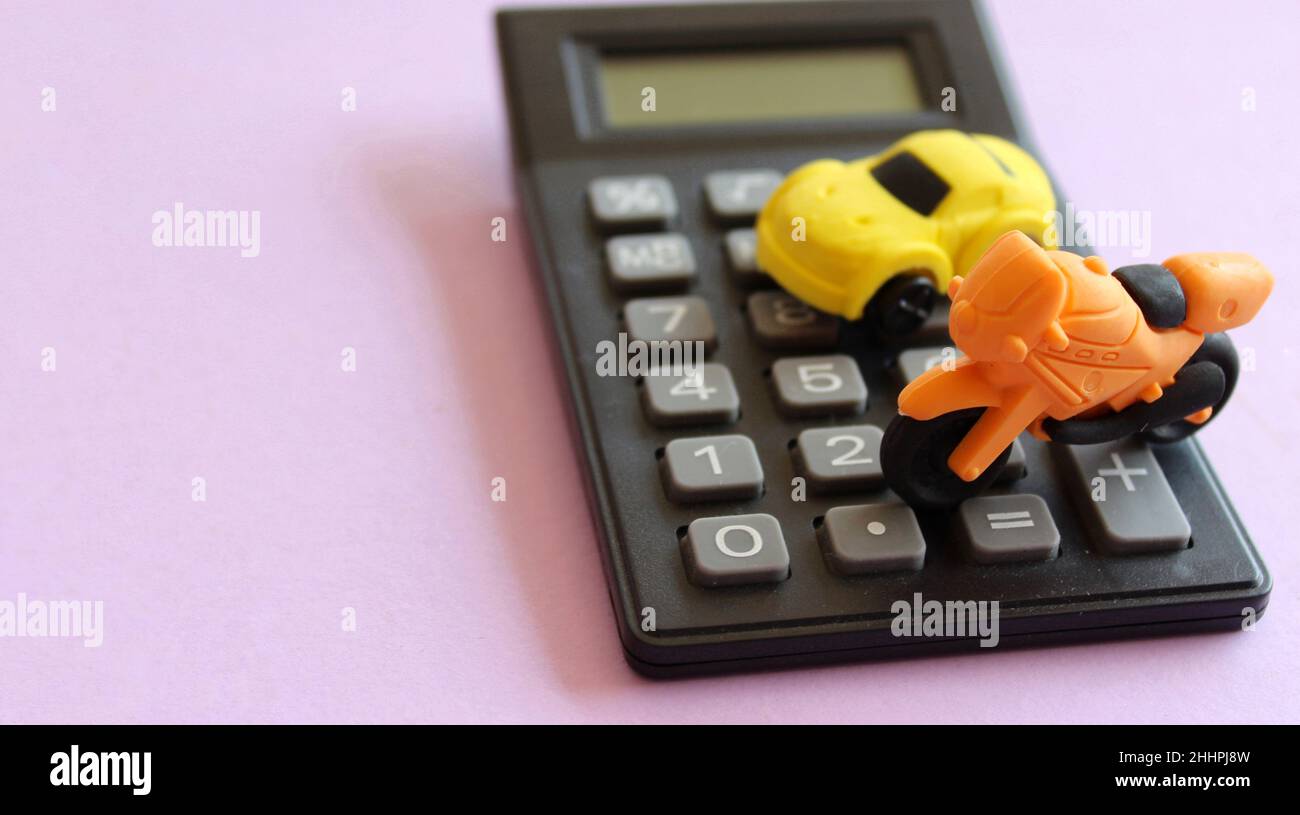 Immagine di messa a fuoco selettiva di moto giocattolo, auto e calcolatrice su sfondo viola. Concetto di calcolo dei costi di trasporto. Foto Stock