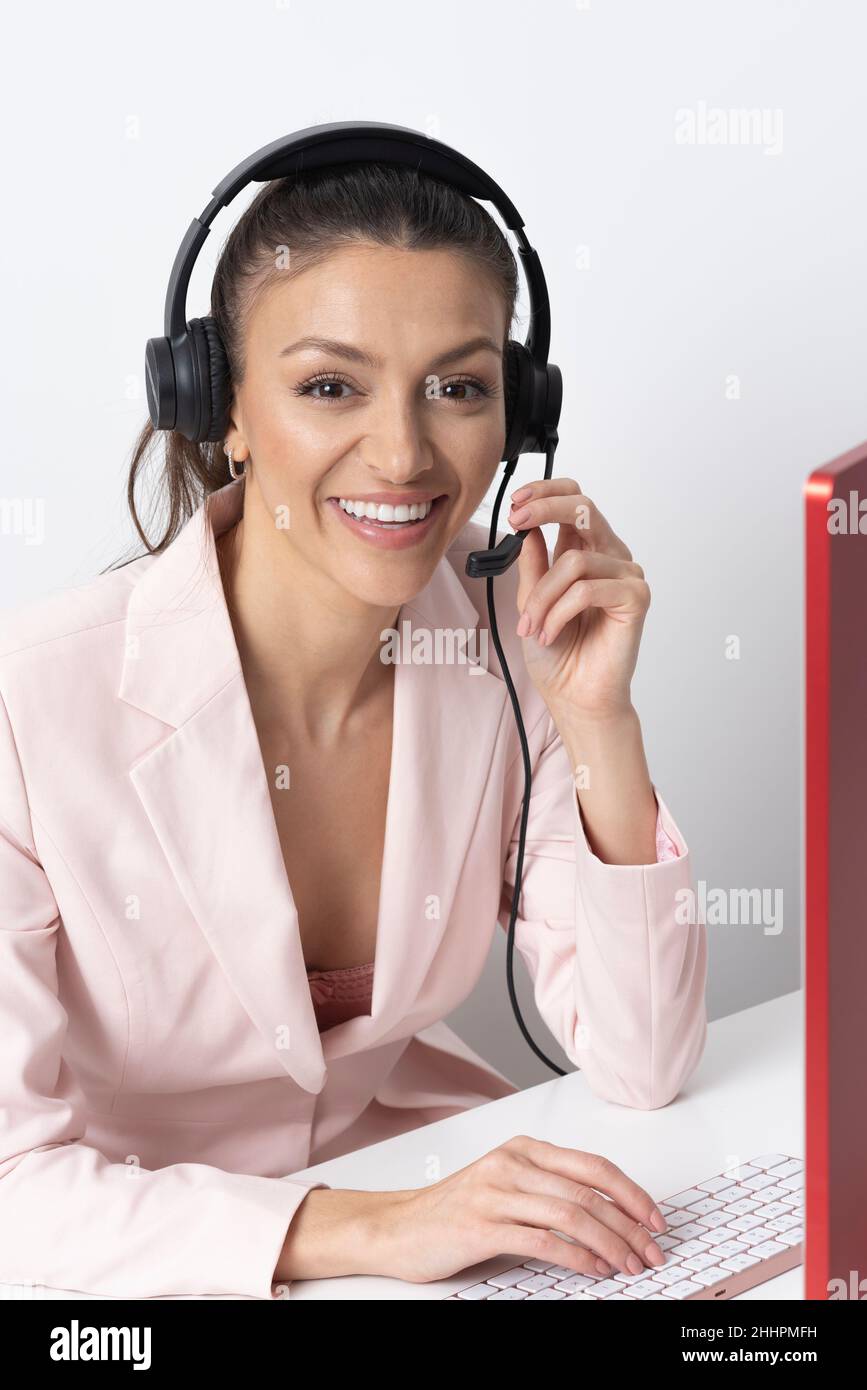 Inghilterra, Regno Unito. 2021. Donna attraente che indossa una cuffia telefonica e una giacca rosa. Foto Stock