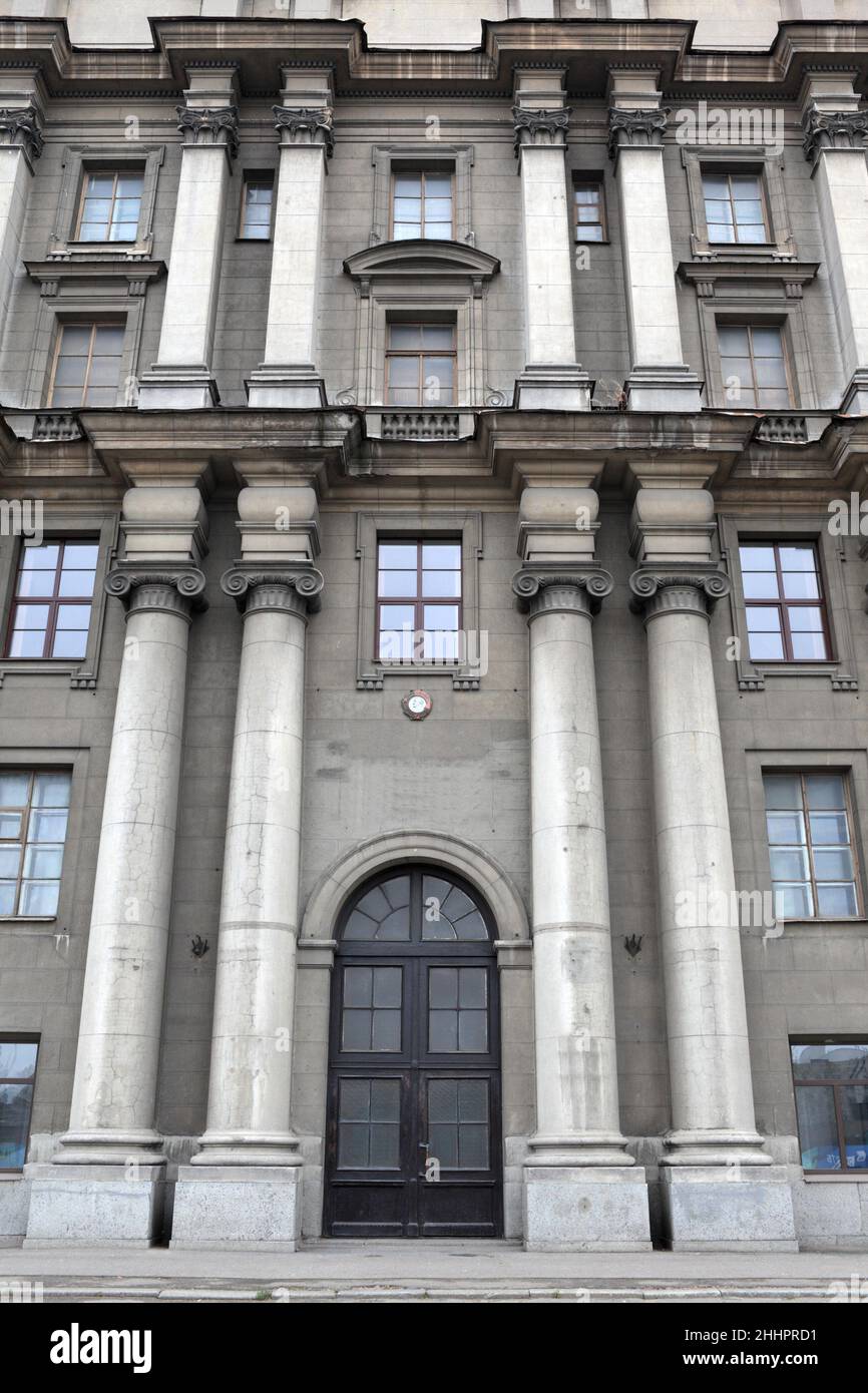 Si trova di fronte a un edificio storico grigio a San Pietroburgo, Russia Foto Stock