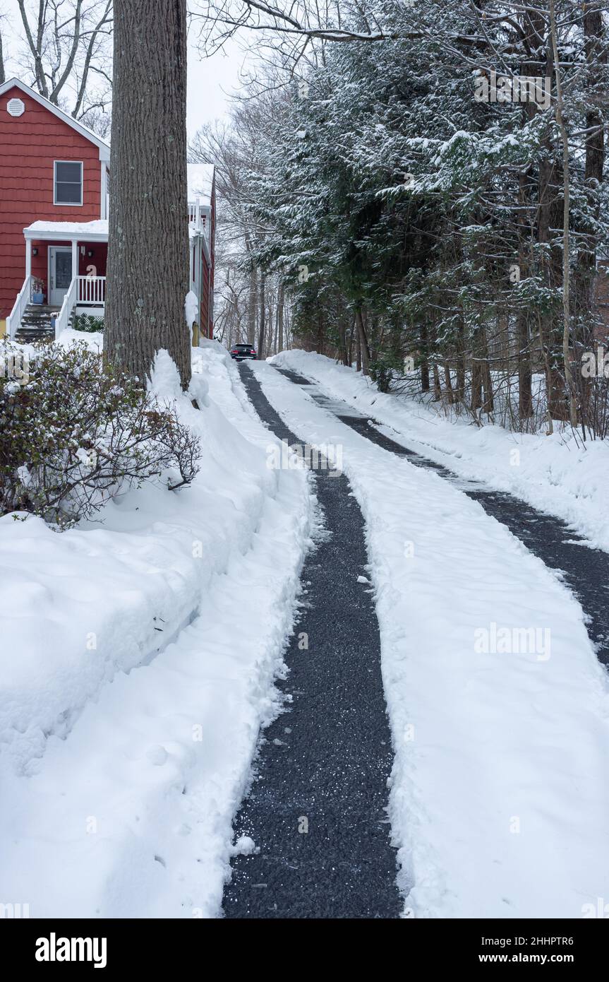 pulizia dei binari dell'auto nel vialetto dopo la tempesta di neve Foto Stock