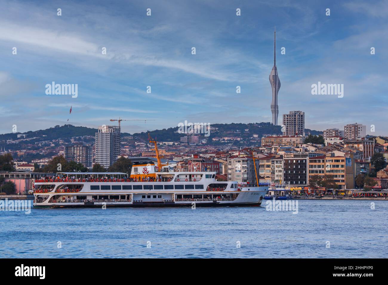 Vista da Kadıköy a Çamlıca Hill, enorme torre di telecomunicazioni sul lato asiatico di Istanbul, traghetto nel mare di marmara su sfondo blu cielo nuvoloso. Foto Stock