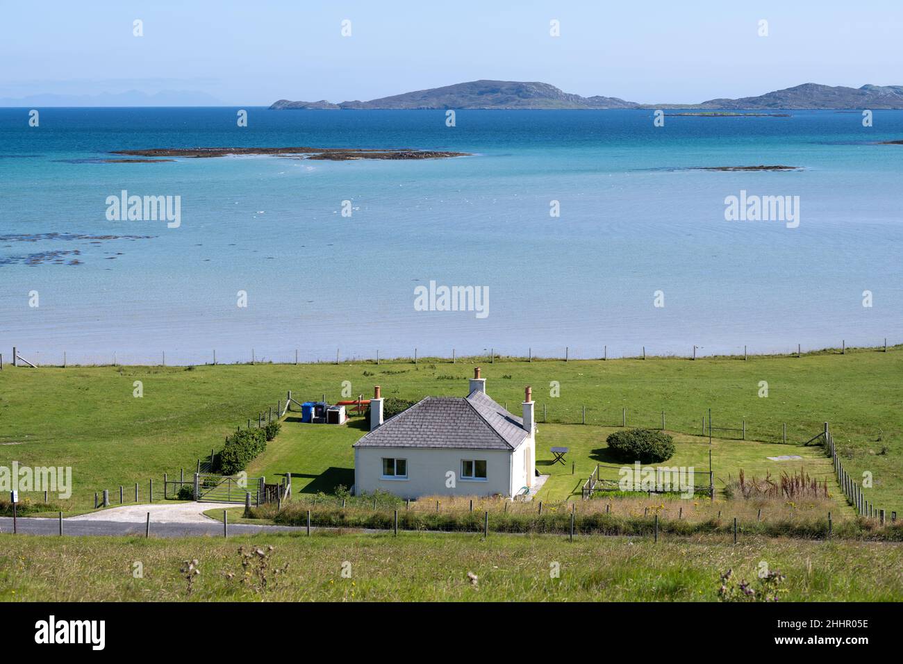 Un cottage residenziale con la piccola isola marea disabitata di Orosay sullo sfondo, Sound of barra, Eoligarry Foto Stock