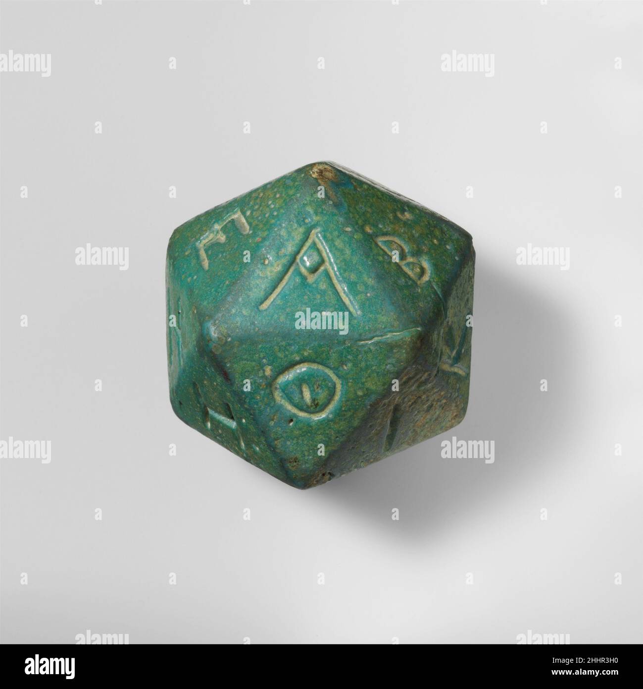 Poliedro di faienza inscritto con lettere dell'alfabeto greco 2nd–3rd secolo d.C. romano un certo numero di poliedri fatti in vari materiali sono conosciuti dal periodo ellenistico e romano. Possono essere stati utilizzati insieme a un oracolo iscritto su un pilastro stabilito in un luogo pubblico. Il poliedro è stato lanciato per scegliere una lettera a caso. Si consultò l'iscrizione per trovare la lettera corrispondente e leggere la risposta dell'oracolo. Ci sarebbero venti messaggi oracolari, ciascuno che inizia con una lettera dell'alfabeto che corrispondeva ad un lato dei dadi. Faience poliedro inscr Foto Stock