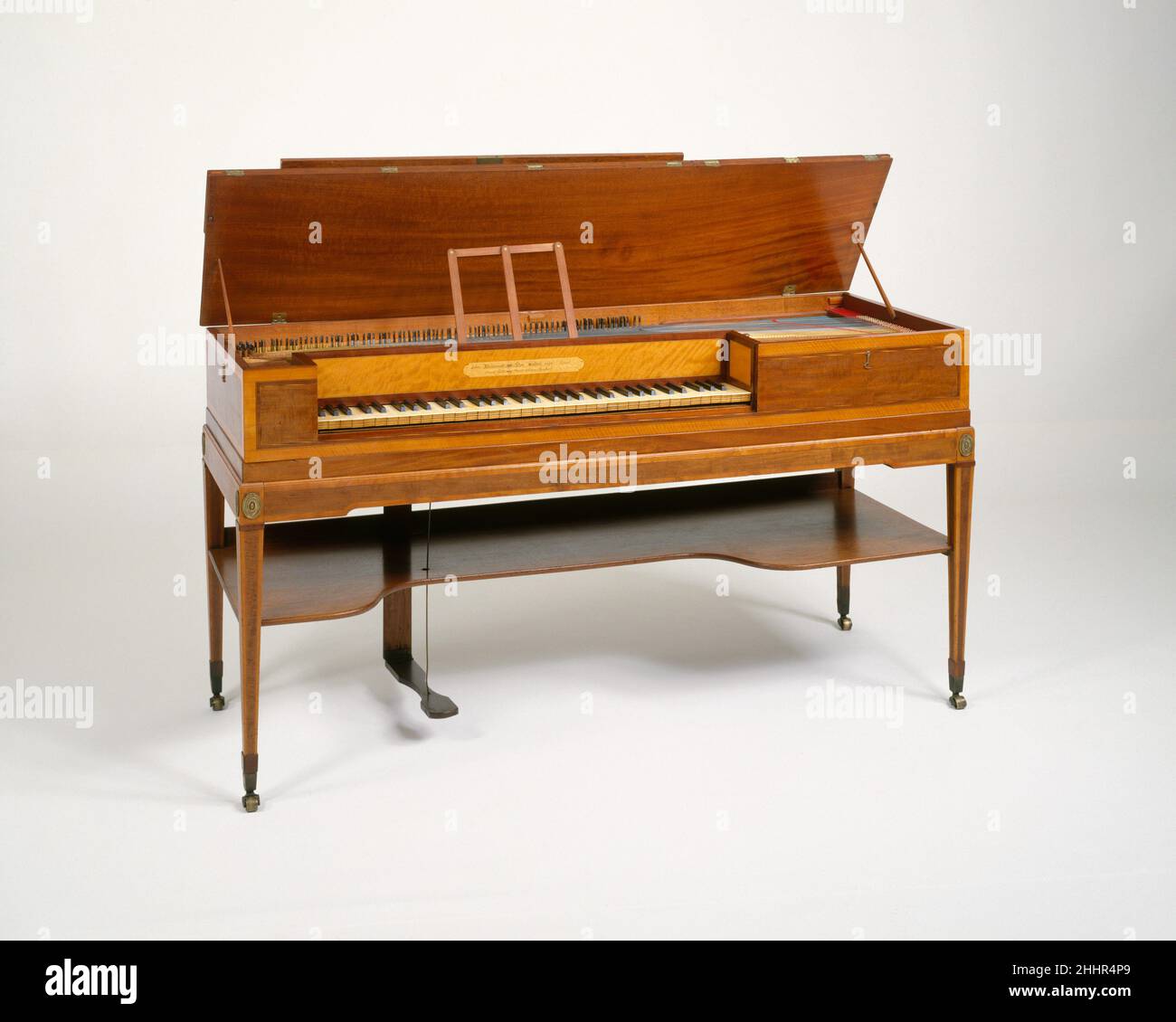 Square piano 1797 John Broadwood & Sons basato sul design di Johannes Zumpe per un semplice piano quadrato, questo elegante strumento incorpora diverse innovazioni. Una bussola estesa di 5-1/2 ottave è possibile con un design che ha tasti si estendono sotto la tavola sonora. I pin di sintonizzazione si sono spostati dal lato destro, dove erano affollati e lontani dalla chiave più bassa ad una disposizione comoda lungo la parte posteriore. Questo pianoforte non dispone di controllo ammortizzatore; il pedale apre l'aletta del coperchio sulla tavola armonica quando il pannello del coperchio principale è chiuso. Broadwood sostituì i finecorsa con i pedali intorno al 1785. Entro il 179 Foto Stock