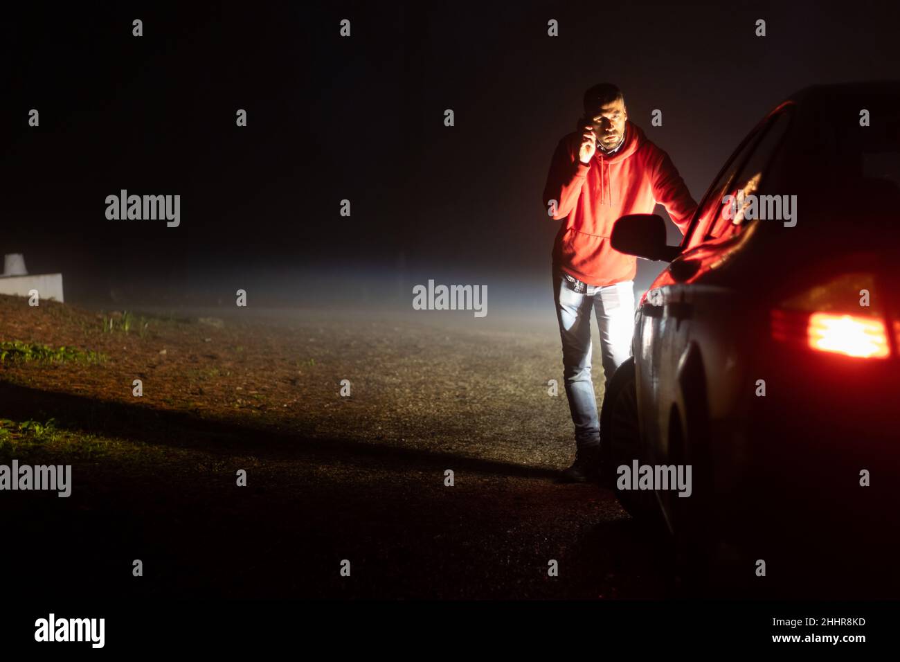 Uomo che chiama compagnia di assicurazione fuori della sua auto rotta Foto Stock