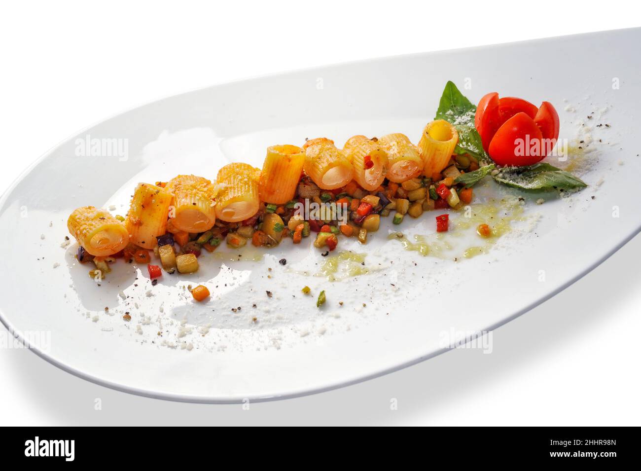 Pasta di maniche con salsa di pomodoro su verdure cotte tagliate con pomodoro ciliegia e foglie di basilico in piatto bianco isolato su sfondo bianco, copia s. Foto Stock