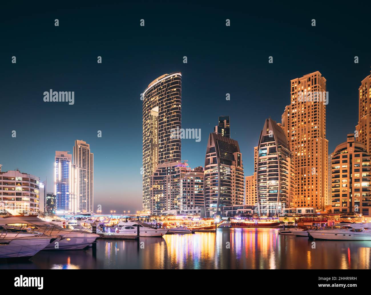 Porto di Dubai Marina, Emirati Arabi Uniti. Jetty con molti barche ormeggiate, Sightseeing Boat nelle illuminazioni notturne. Vista notturna di Dubai Foto Stock