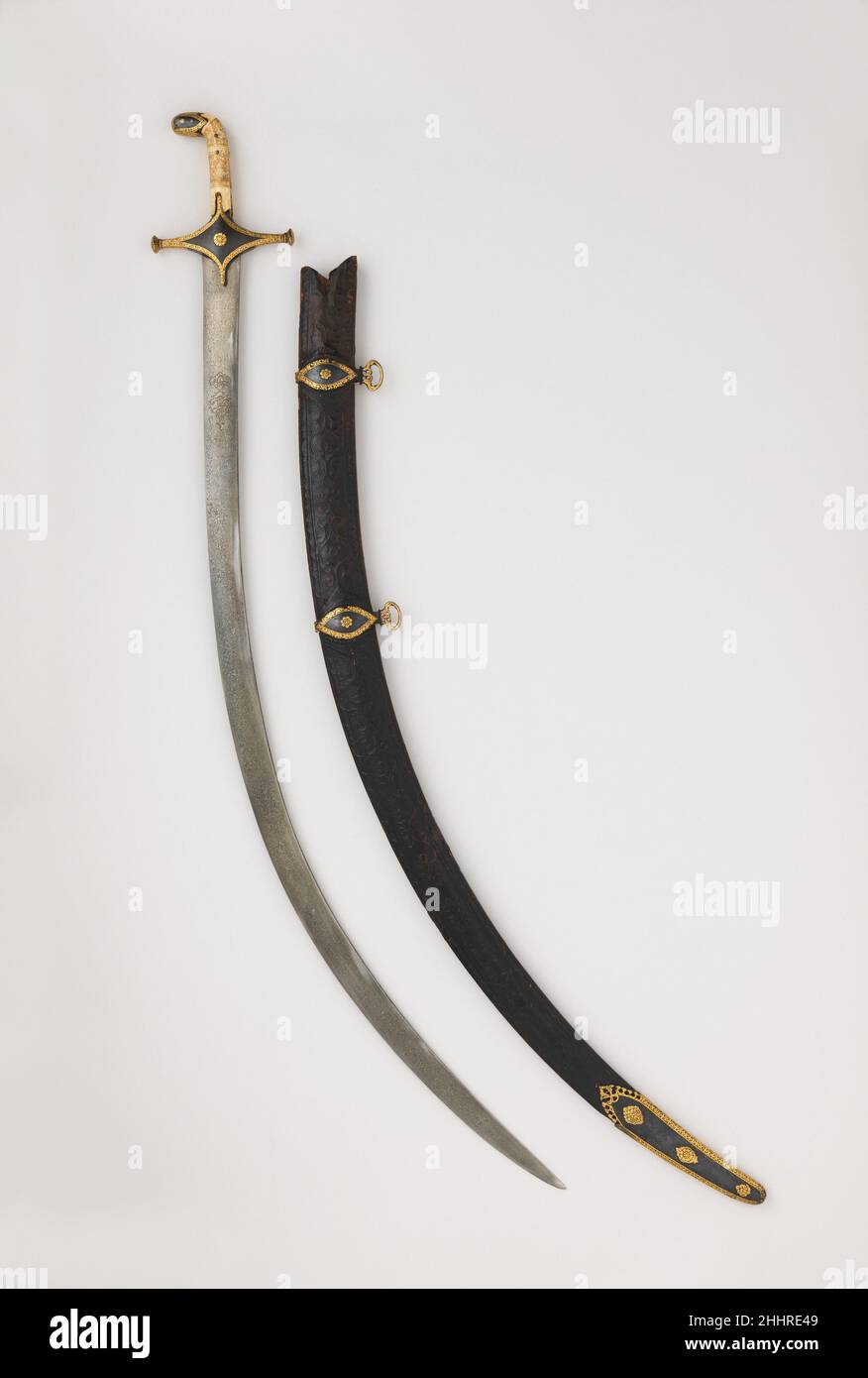 Sabre con lama di scabbard possibilmente datata a A.H. 1191/A.D. 1777–78 Persiano questo è un classico esempio di sciamano iraniano di alta qualità del XVIII secolo. La lama di acciaio crogiolo (“annaffiato”) porta i nomi del leggendario spadullah iraniano di Isfahan e del suo patrono Shah ‘Abbas i di Persia (r. 1588–1629). Poiché il nome di Aguadullah si trova su lame inscritte con date che vanno dal XV al XIX secolo, è probabile che la maggior parte delle firme siano false. Sabre con scabbard 32739 Foto Stock