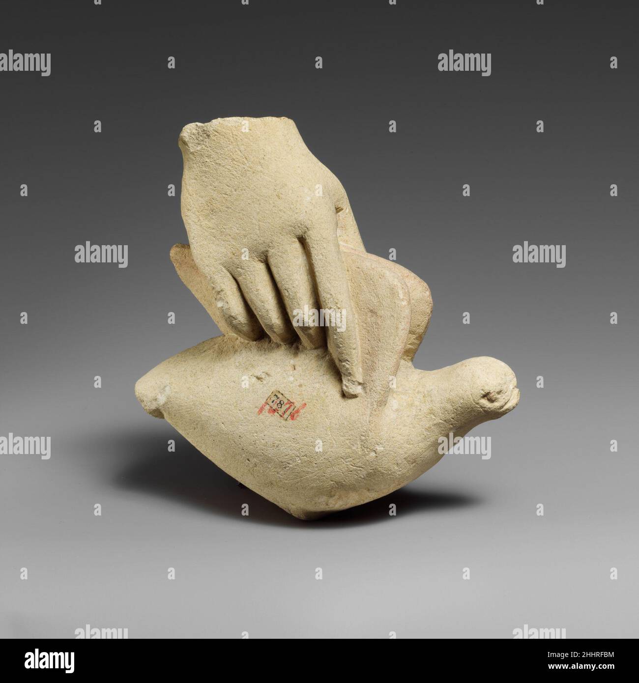 Mano calcarea che tiene una colomba cipriota Una piccola mano destra tiene una colomba dalle ali. Si è verificato un'interruzione sulla superficie interna. Mano di calcare che tiene una colomba 242270 Foto Stock