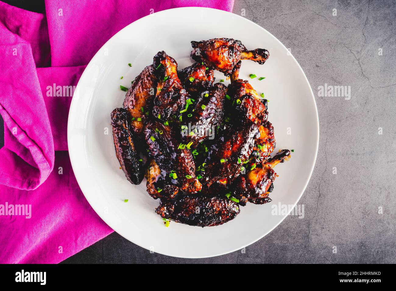 Cinese cinque ali di pollo alle spezie con soia, glassa di riduzione balsamica: Piatto di wingette di pollo appiccicose e drumette guarnite con erba cipollina Foto Stock