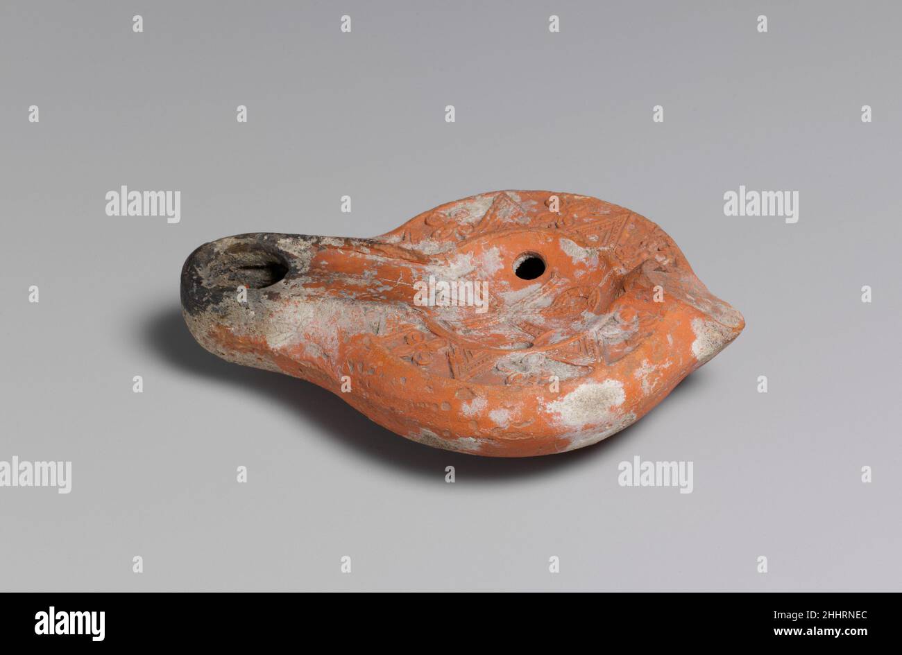 Lampada 5th–6th secolo piccole lampade in terracotta realizzate con stampi doppi sono state la fonte di luce più comunemente utilizzata nella vita quotidiana copta. Uno stoppino prodotto da fibra vegetale o tessuto di lino è stato posto in un serbatoio riempito di olio, generalmente olio di ricino o sesamo, e illuminato. Il disco di questa lampada è decorato con un monogramma chi-rho, costituito dalle lettere maiuscole greche sovrapposte chi (X) e rho (P), le prime due lettere di Cristo in greco. Il monogramma perlato è invertito e circondato da un bordo alternato di chevron e quatrefoil.Christian simboli come questo monogramma sono stati tho Foto Stock