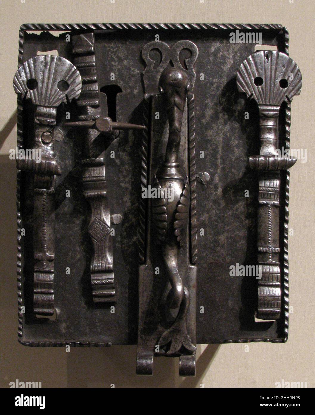 Serratura a cassettiera e chiave probabilmente all'inizio del 16th secolo spagnolo il santuario di San Giacomo il Grande alla cattedrale di Santiago da Compostela era uno dei luoghi di pellegrinaggio più popolari del Medioevo. Cockleshell emblemi del santo apparso ovunque in ornamento spagnolo, dalle teste delle unghie alle griglie della finestra. Appaiono sull'estremità inferiore dei due punti metallici giganti con cui questa serratura era attaccata ad una cassa o ad un petto. Un mostro alare con una coda di pesce ornano la nasca della serratura; un balaustro girevole nasconde la serratura. Chiave e serratura del coffer. Spagnolo. Probabilmente all'inizio del 16th secolo. Ferro battuto. Foto Stock