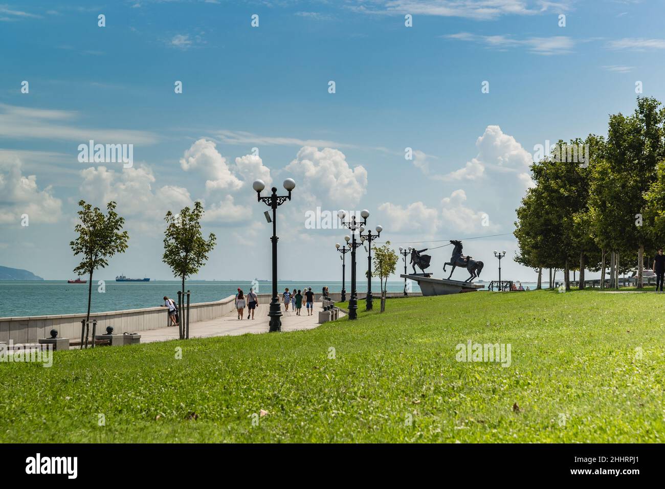 Novorossiysk, Russia, 16 agosto 2021: Nuovo argine e scultura genere Exodus in una giornata estiva soleggiata. Navi da carico nella baia di Tsemesskaya Foto Stock