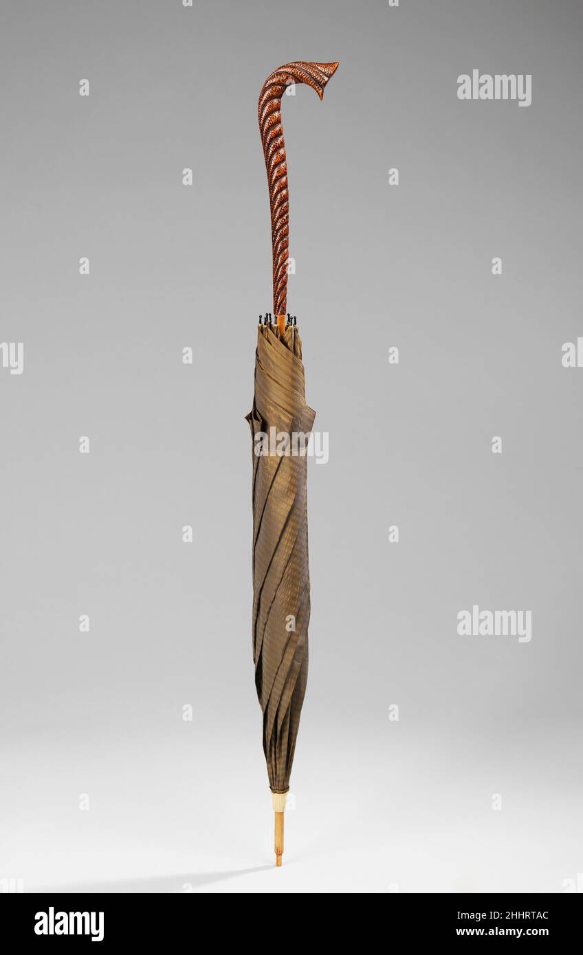 Ombrello 1888 americano prima della diffusa produzione di massa dell'abbigliamento nel 20th secolo, le sagome alla moda cambiarono più lentamente, mentre i piccoli dettagli e gli elementi decorativi erano al centro dell'attenzione del rapt e del rapido cambiamento. Nell'industria degli ombrelli e degli ombrelloni, la novità era costantemente richiesta dai produttori stessi, in quanto il suo prodotto non poteva essere facilmente creato in casa o da un artigiano locale esperto. La ricerca dell'invenzione è vista in questo ombrello dalla collezione Brooklyn, dove il tessuto ha un effetto visivo molto interessante non a differenza di una pietra occhio della tigre, e Th Foto Stock