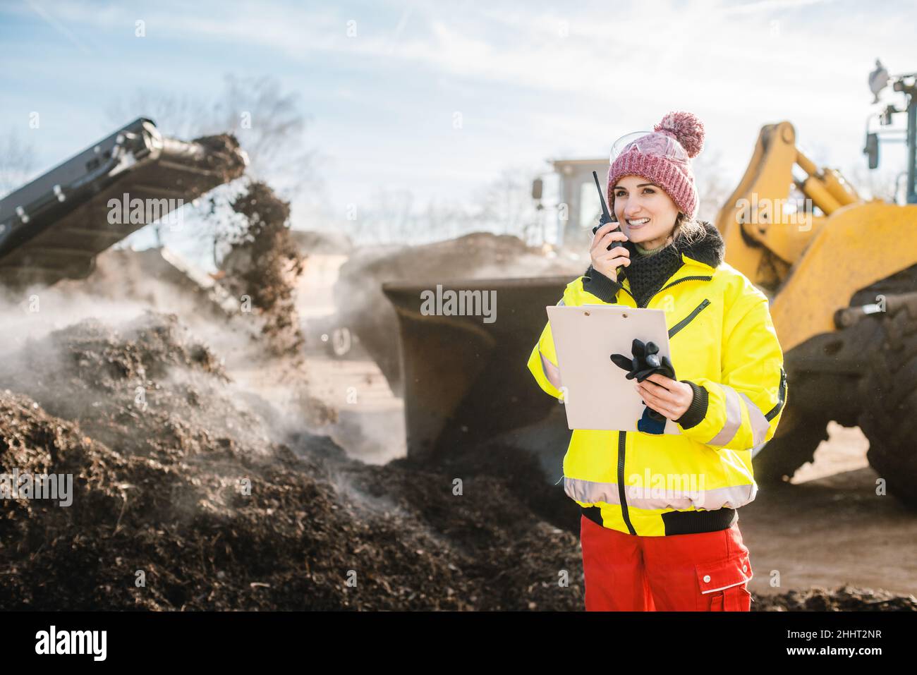 Responsabile delle operazioni di biomassa e discarica utilizzando la radio di fronte alle macchine Foto Stock