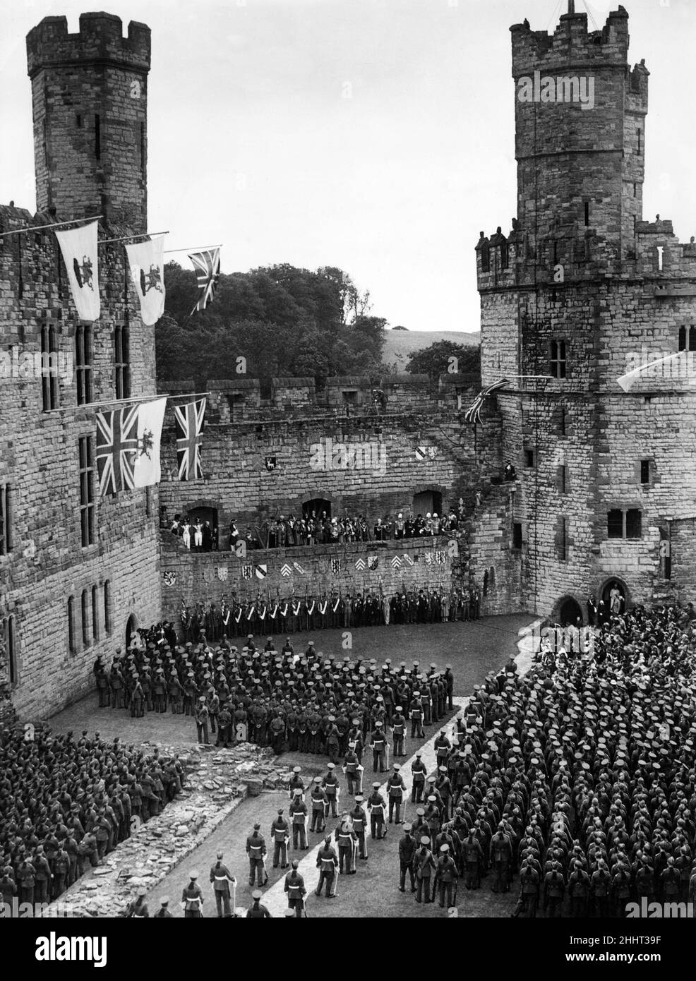 All'interno delle mura storiche del Castello di Caernarfon uomini del Royal Welch Fusiliers, passato e presente, ascoltare il discorso di Lloyd George, Constable del Castello, nel 250th anniversario dell'innalzamento di questo famoso reggimento. 1939. Foto Stock