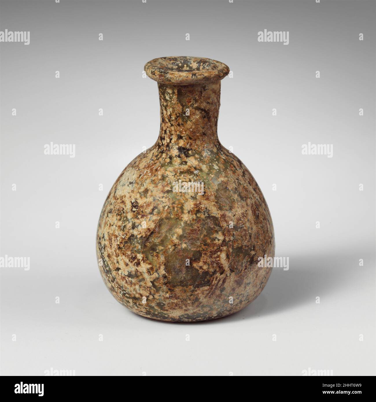 Bottiglia di profumo in vetro ca. 1st–2nd secolo d.C. romano traslucido blu pallido verde.spesso rovesciata, bordo orizzontale, con labbro esterno arrotondato e scanalatura circolare sulla superficie superiore; collo corto, cilindrico, rastremato verso il basso; corpo ovoide; Fondo piatto con Center.intact leggermente concavo; molte bolle di pinprick; vaiolatura, dulling, e cremoso marrone intempering.. Bottiglia di profumo in vetro 244624 Foto Stock