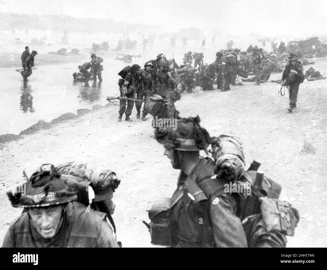 Truppe della divisione di fanteria del 3rd atterrano sulla spiaggia rossa della regina, zona di spada, all'inizio del 6th giugno 1944, la prima formazione britannica atterrare a Sword Beach. In primo piano sono i sappers di 84 Field Company Royal Engineers, parte del No.5 Beach Group, identificati dalle bande bianche intorno ai loro caschi. Dietro di loro, ordini medici di 8 ambulanza di campo, RAMC, può essere visto aiutare gli uomini feriti. In background i commandos di 1st Brigade Special Service possono essere visti sbarcare dal loro LCI(S) nave da sbarco. 6th giugno 1944 Foto Stock