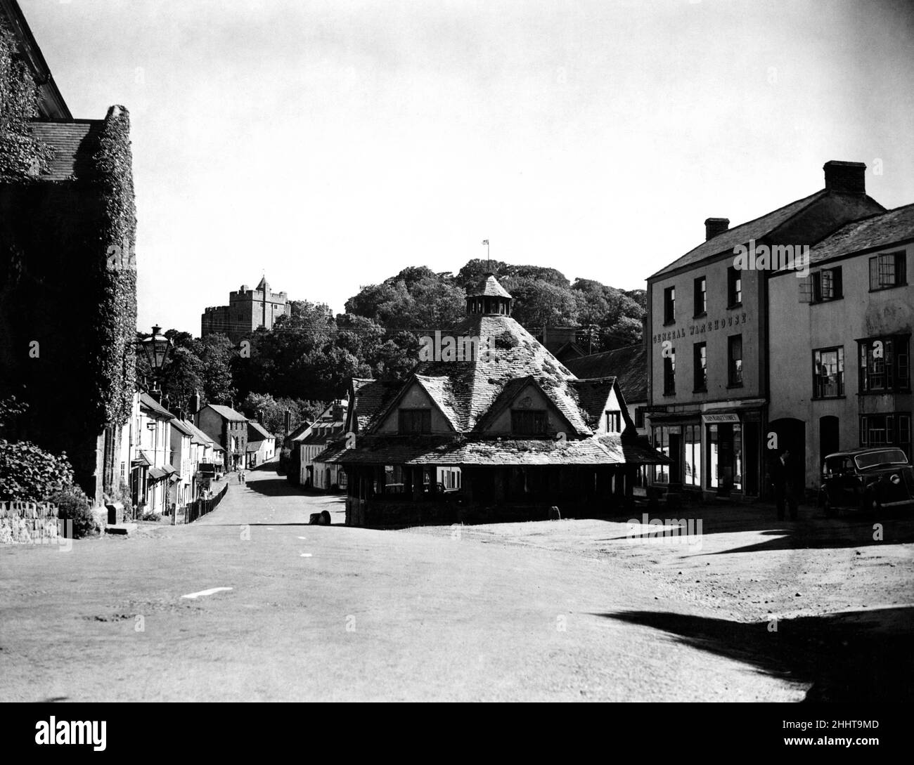 Una gemma di antichità rustica, la bellissima Dunster, Somerset, fu metà dimenticata quando il motorista posò la sua auto durante gli anni della guerra. Ma presto questo angolo incontaminato dell'Inghilterra accoglierà nuovamente i turisti. Nella foto, il mercato dei filati con il castello di Dunster sullo sfondo nella strada principale ancora deserta. 25th giugno 1945. Foto Stock