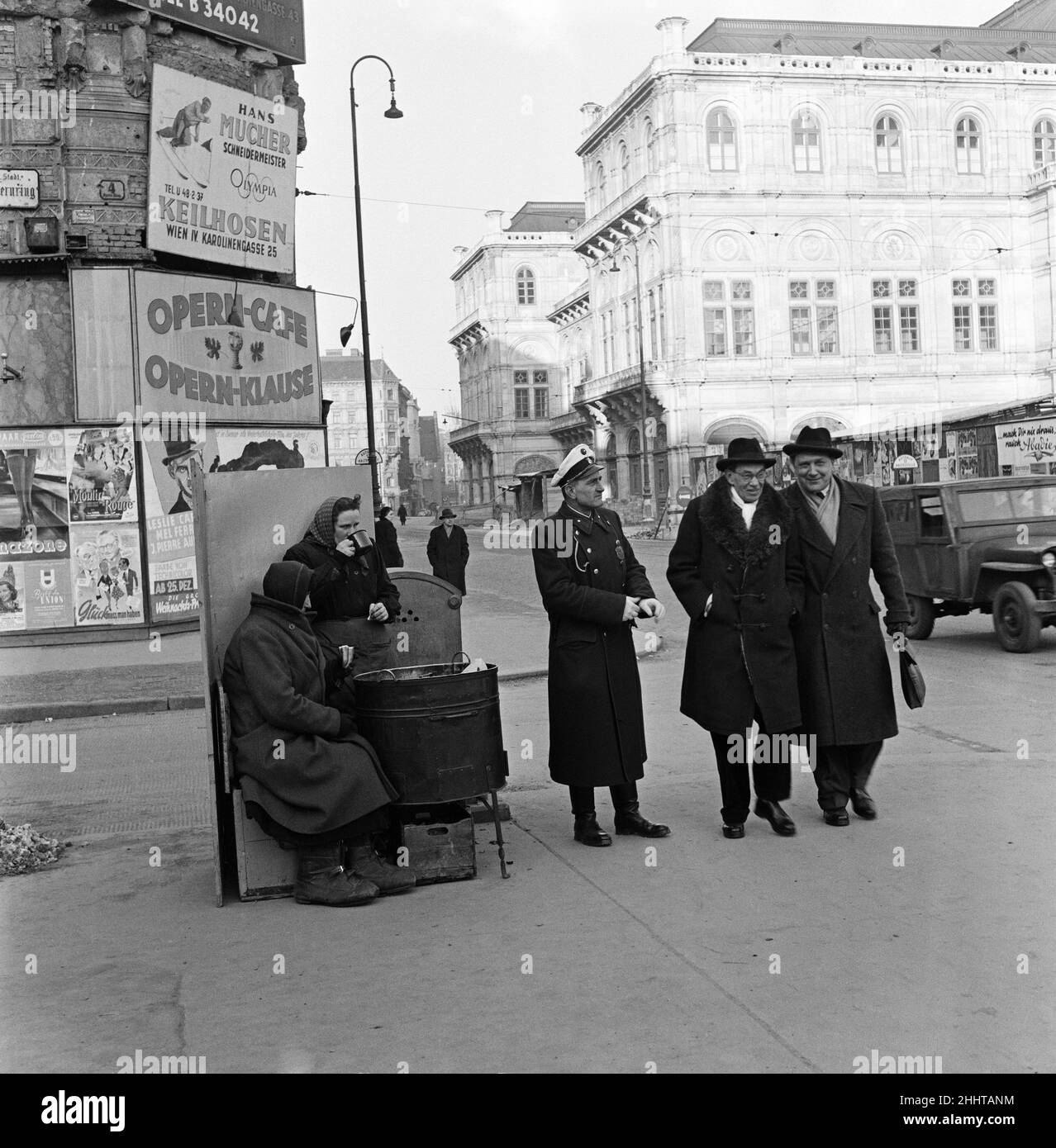 Le castagne calde non sono sufficienti per mantenere caldo a Vienna. Lottano per mantenere caldo sull'angolo. È castagne calde per la polizia stradale. Sono cappotti in pelliccia per i signori. Le donne bevono caffè caldo., anche loro hanno uno scudo dal vento mordente. Vienna, Austria. Febbraio 1954. Foto Stock