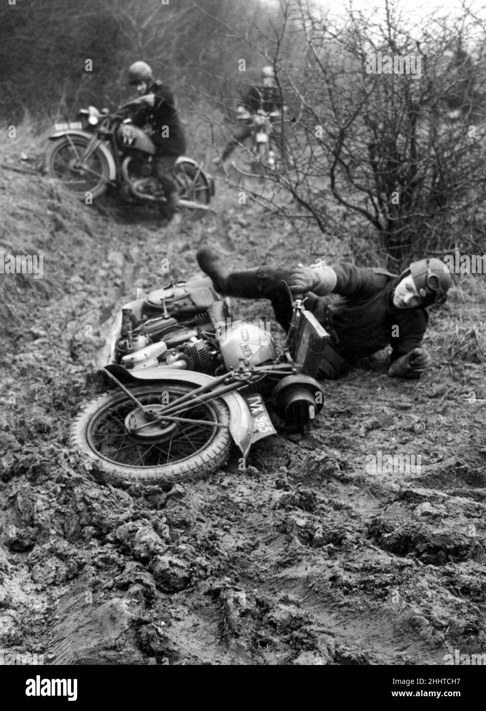 National Fire Service dispatch rider of Number 36 Fire Force Area esercitandosi su un campo d'assalto a Chigwell, Essex che ha crateri bomba, trappole per scivoloni e altri ostacoli che sono progettati per addestrarli a blitz conditions.One rider cade dalla sua bicicletta nel fango denso durante il corso. 11th gennaio 1944. Foto Stock