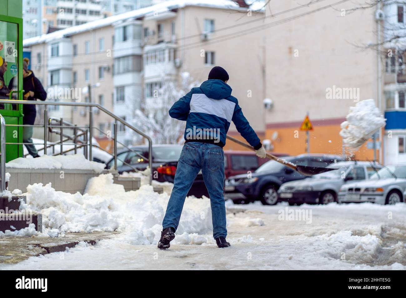 Krasnodar, Russia - Gennaio 24 2022: Uomo rimozione neve con una pala. Vovolando strada da neve coperta caduta Foto Stock