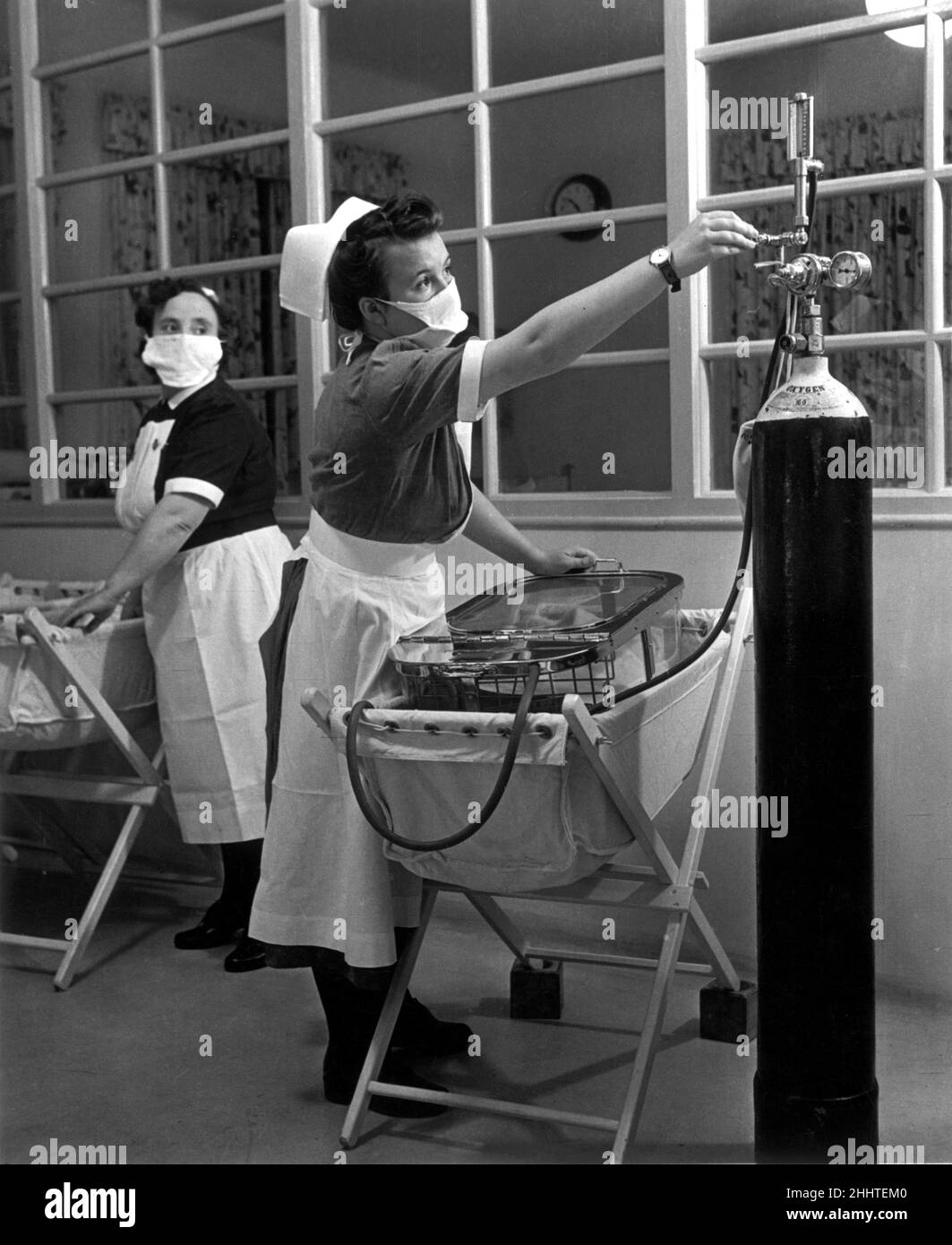 Un infermiere nell'unità di maternità di un ospedale tiene d'occhio la pressione dal ciclante di ossigeno, mentre si preoccupano per una bambina lillte. Gennaio 1949. Foto Stock