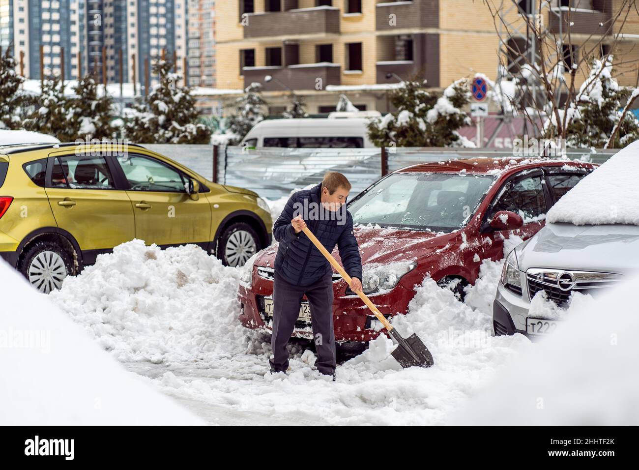Krasnodar, Russia - Gennaio 24 2022: Uomo anziano rimozione neve con una pala. Vovolando strada da neve coperta caduta Foto Stock