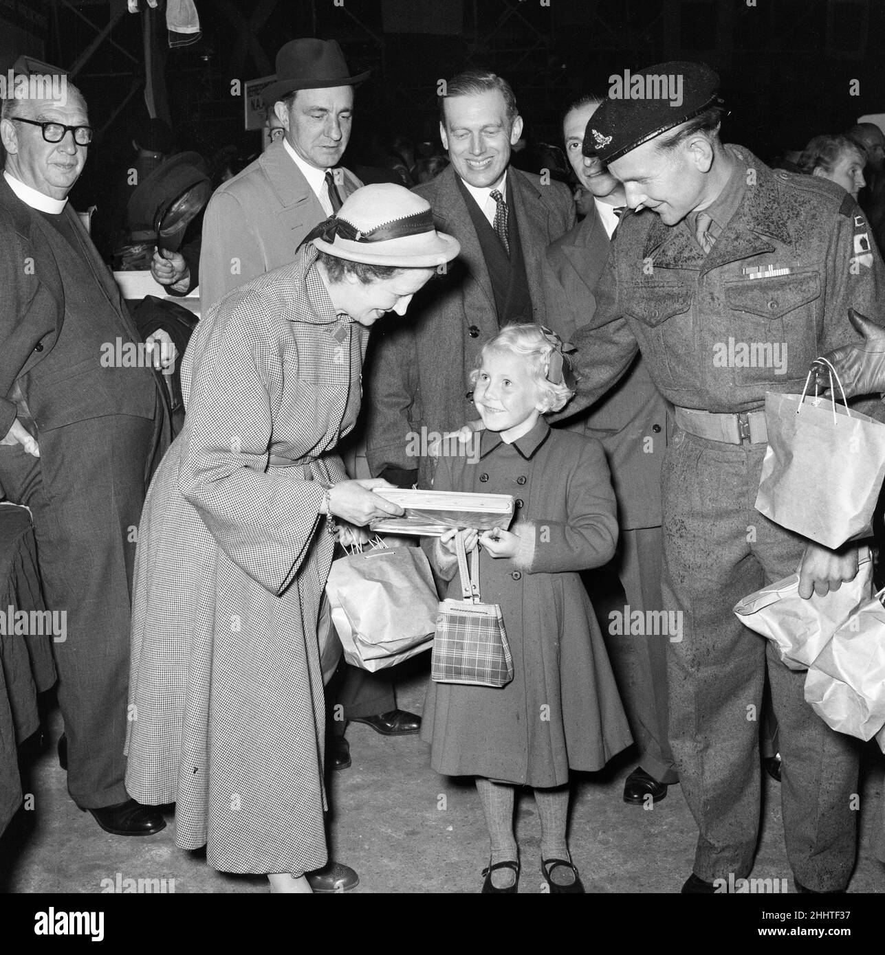 Prigionieri di guerra britannici liberati dalla Corea, raffigurati al loro ritorno a Southampton, dove si ancorarono alle Asturius. Lady Victor Paget che dà i pacchi al soldato di ritorno Collins del reggimento di Gloucester e la sua figlia di sei anni ai capannoni di Southampton. 16th settembre 1953. Foto Stock