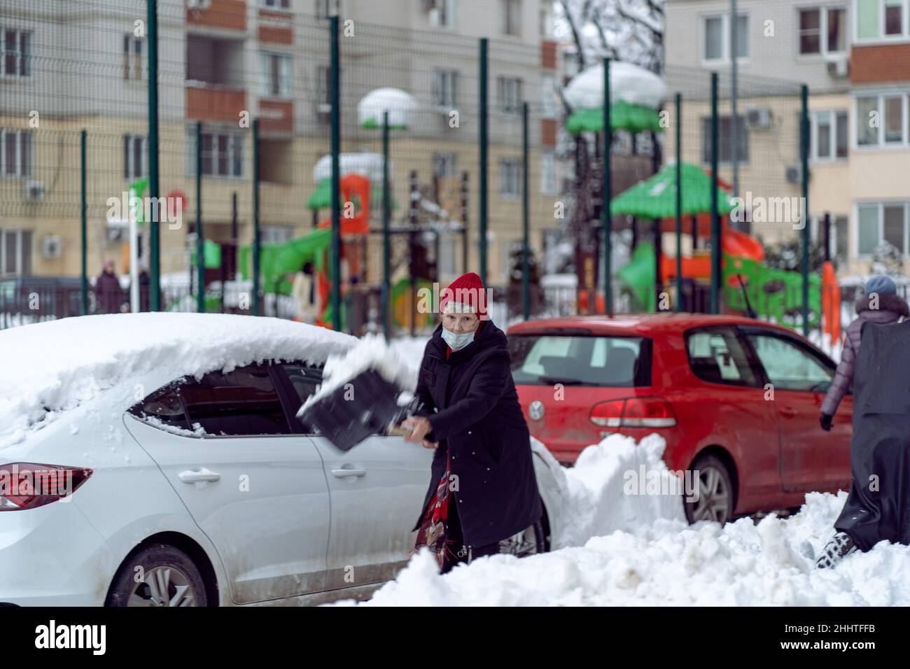 Krasnodar, Russia - Gennaio 24 2022: Donna anziana rimozione neve con una pala. Vovolando strada dalla caduta della neve Foto Stock