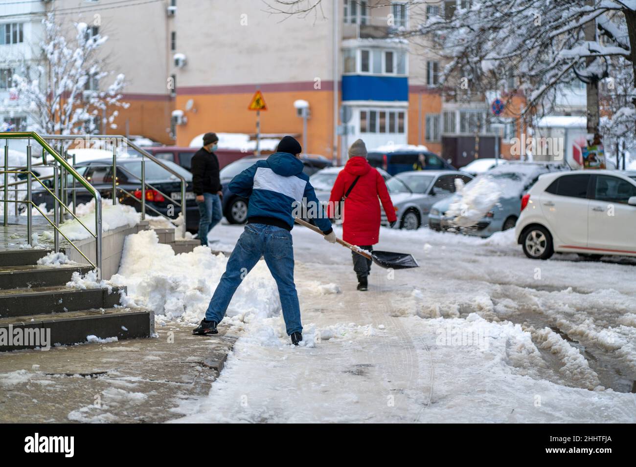 Krasnodar, Russia - Gennaio 24 2022: Uomo rimozione neve con una pala. Vovolando strada da neve coperta caduta Foto Stock